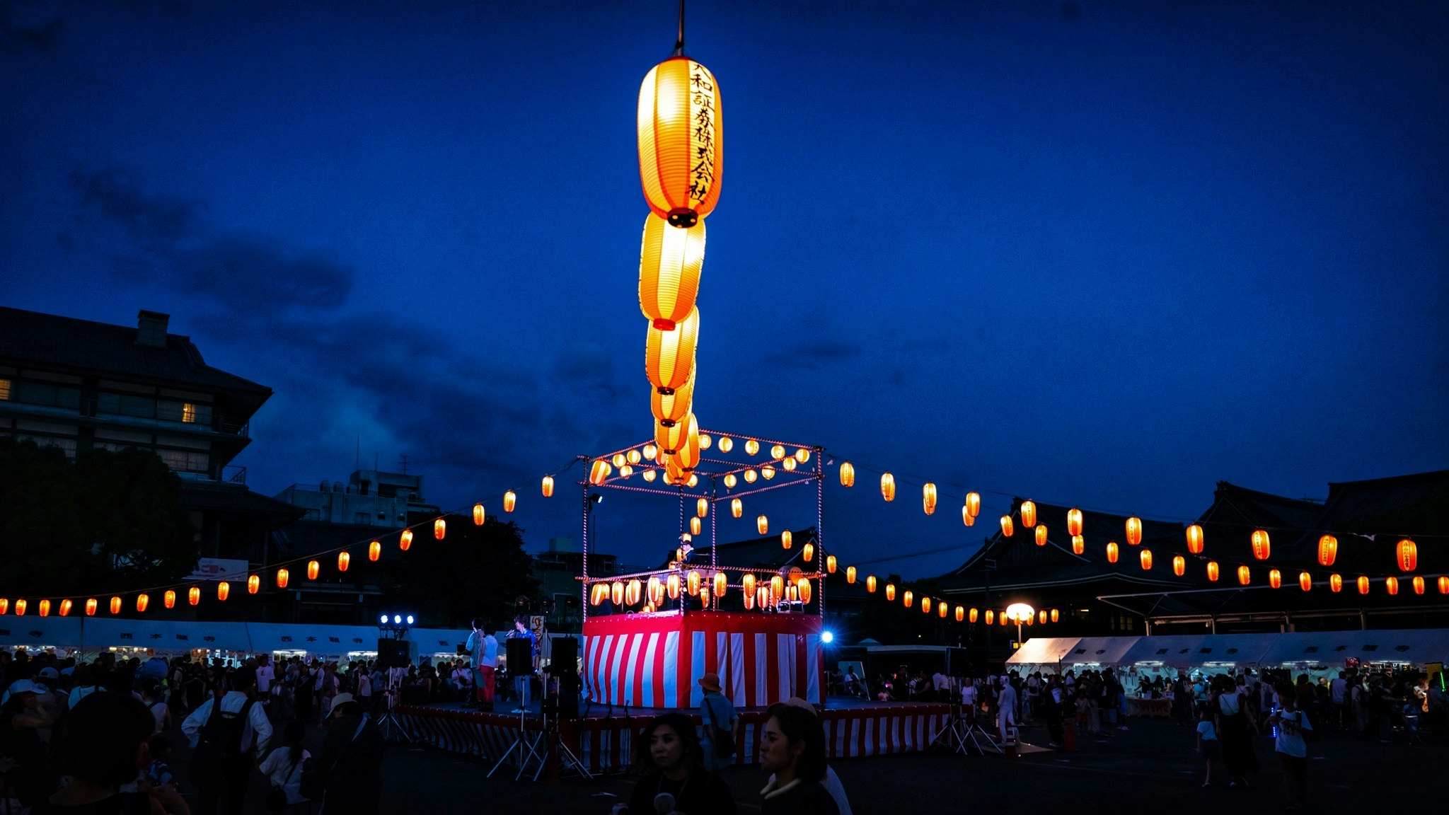 夜空の下で灯籠と提灯が並ぶ盆踊りの夏祭り会場