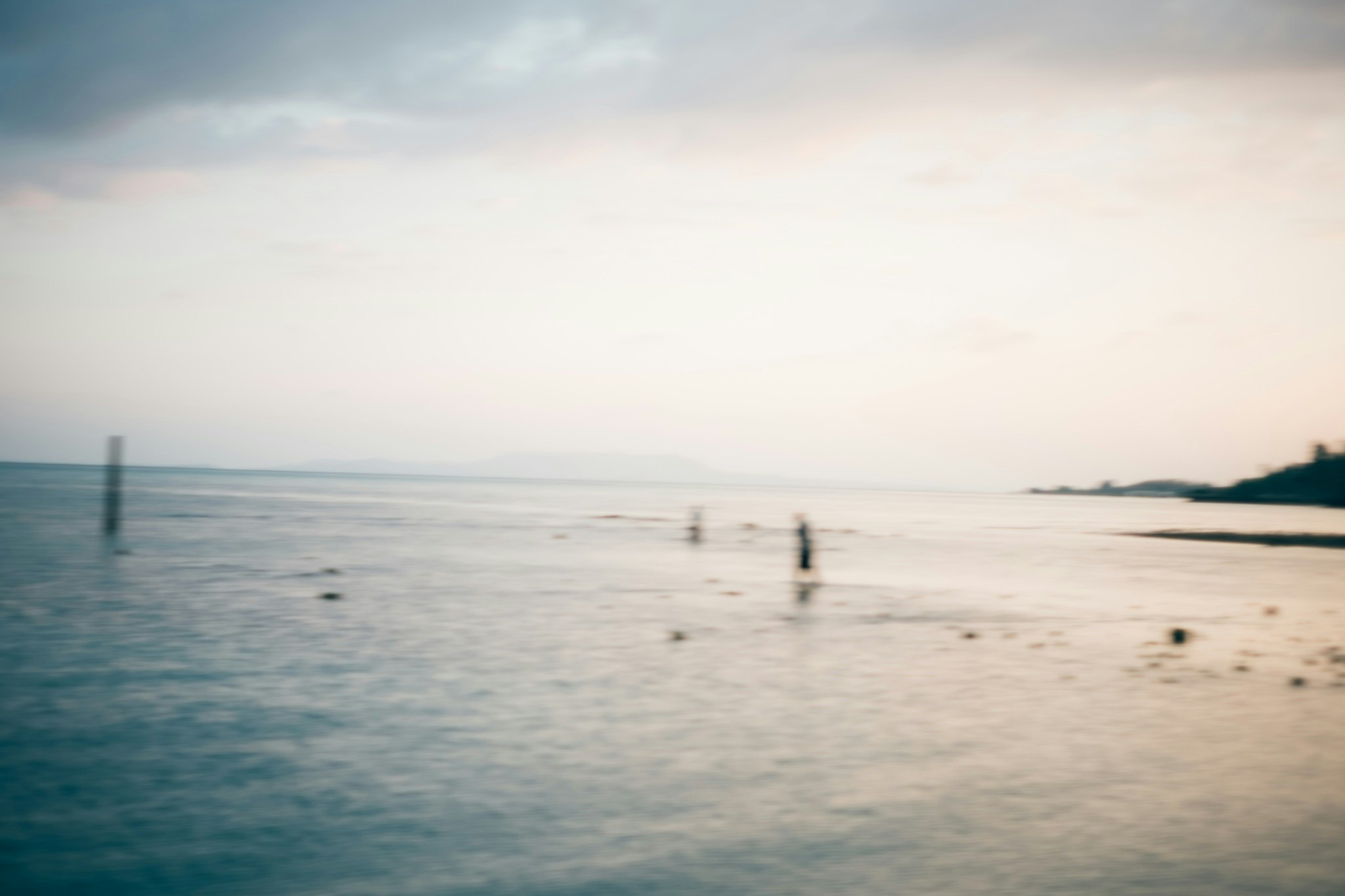 Nelayan mulai bekerja di tepi pantai yang tenang, siluet jauh
