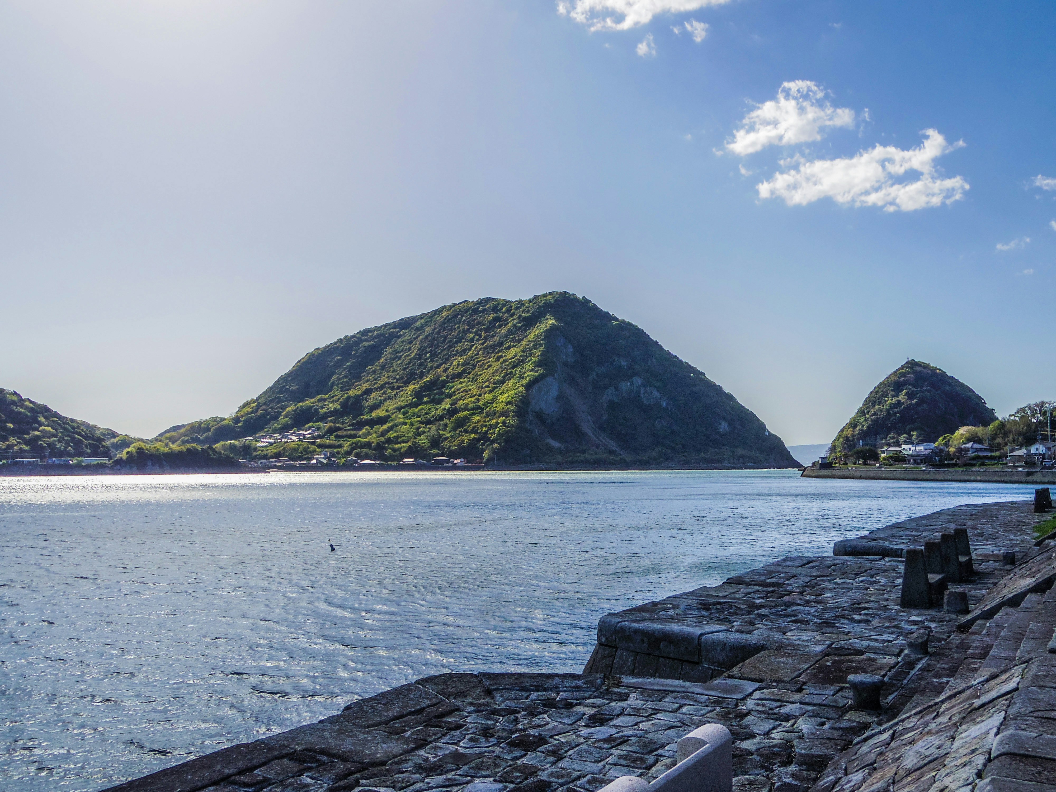 海沿いの石造りの防波堤と小島のある湾の風景