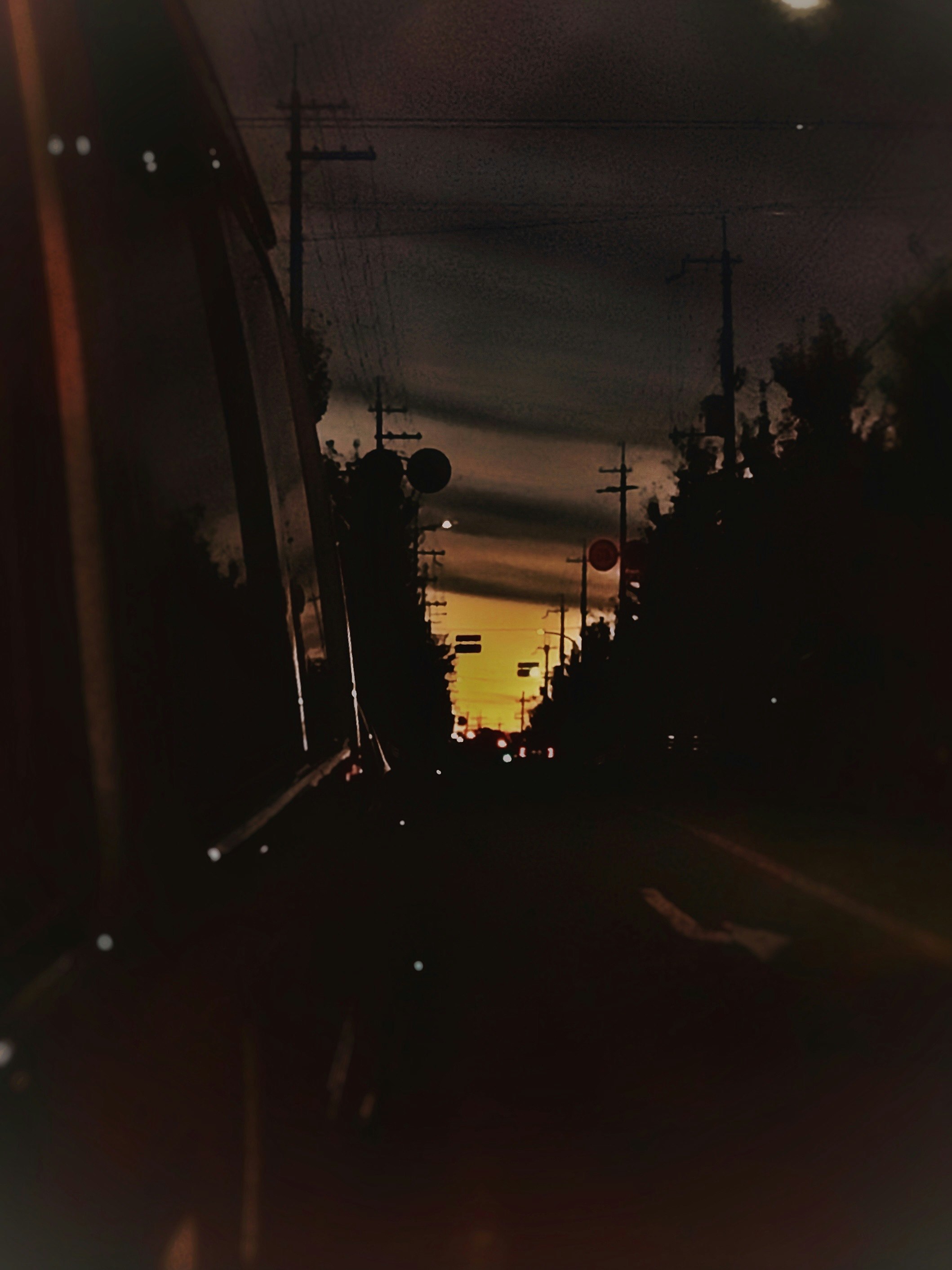 夕焼けの車道をバックミラー越しに見た後方の景色