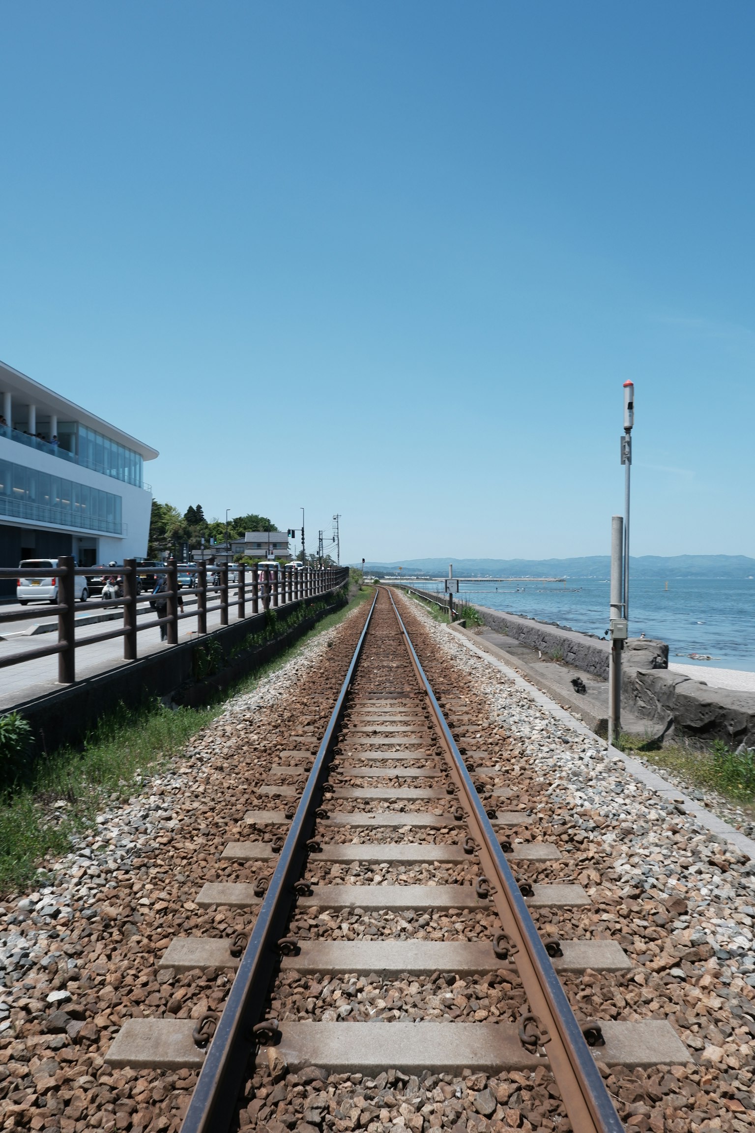 Binari ferroviari costieri che conducono al mare sotto un cielo azzurro