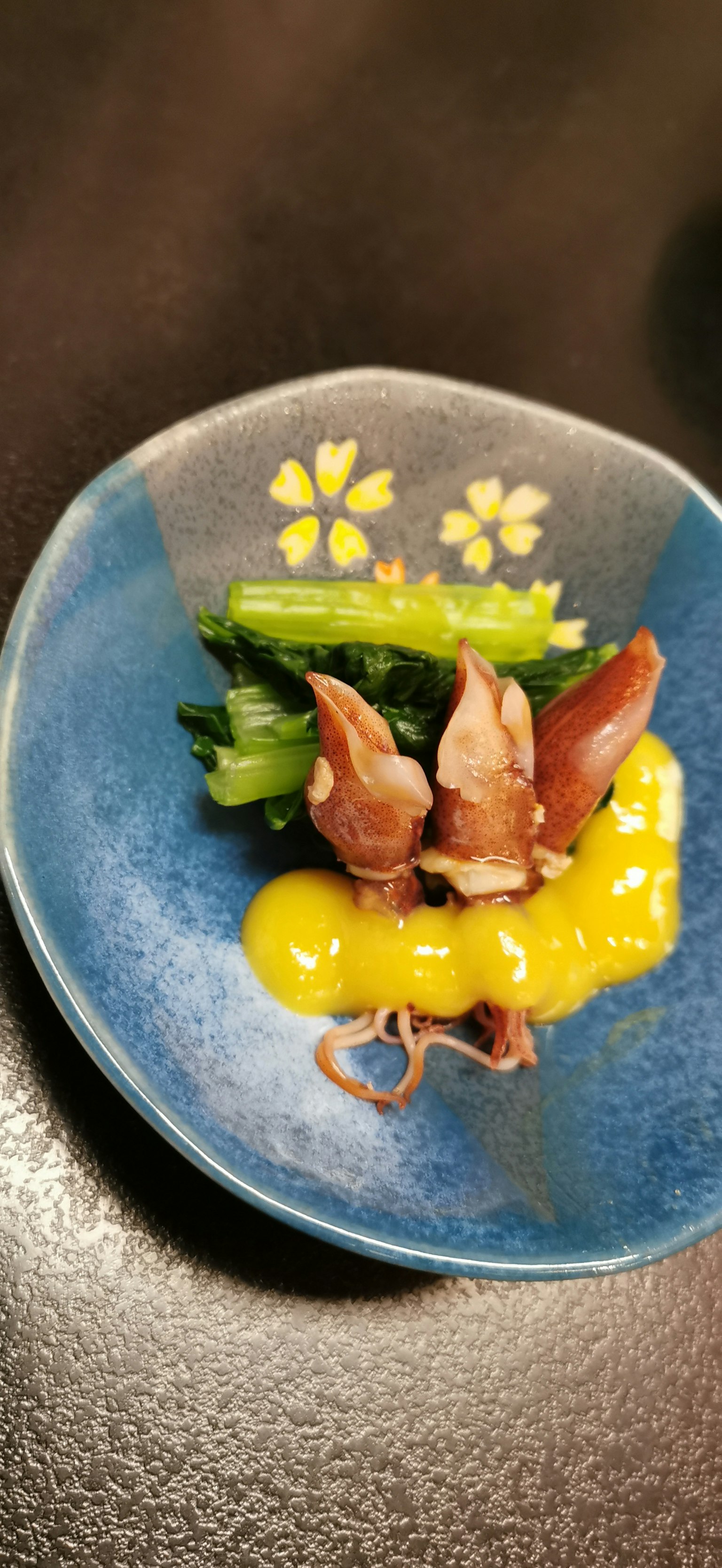 Un petit plat avec du calmar et du jaune d'œuf sur une assiette bleue