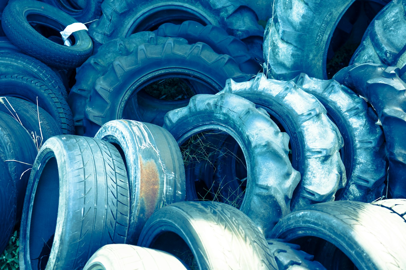 Una pila di pneumatici blu impilati con dell'erba visibile