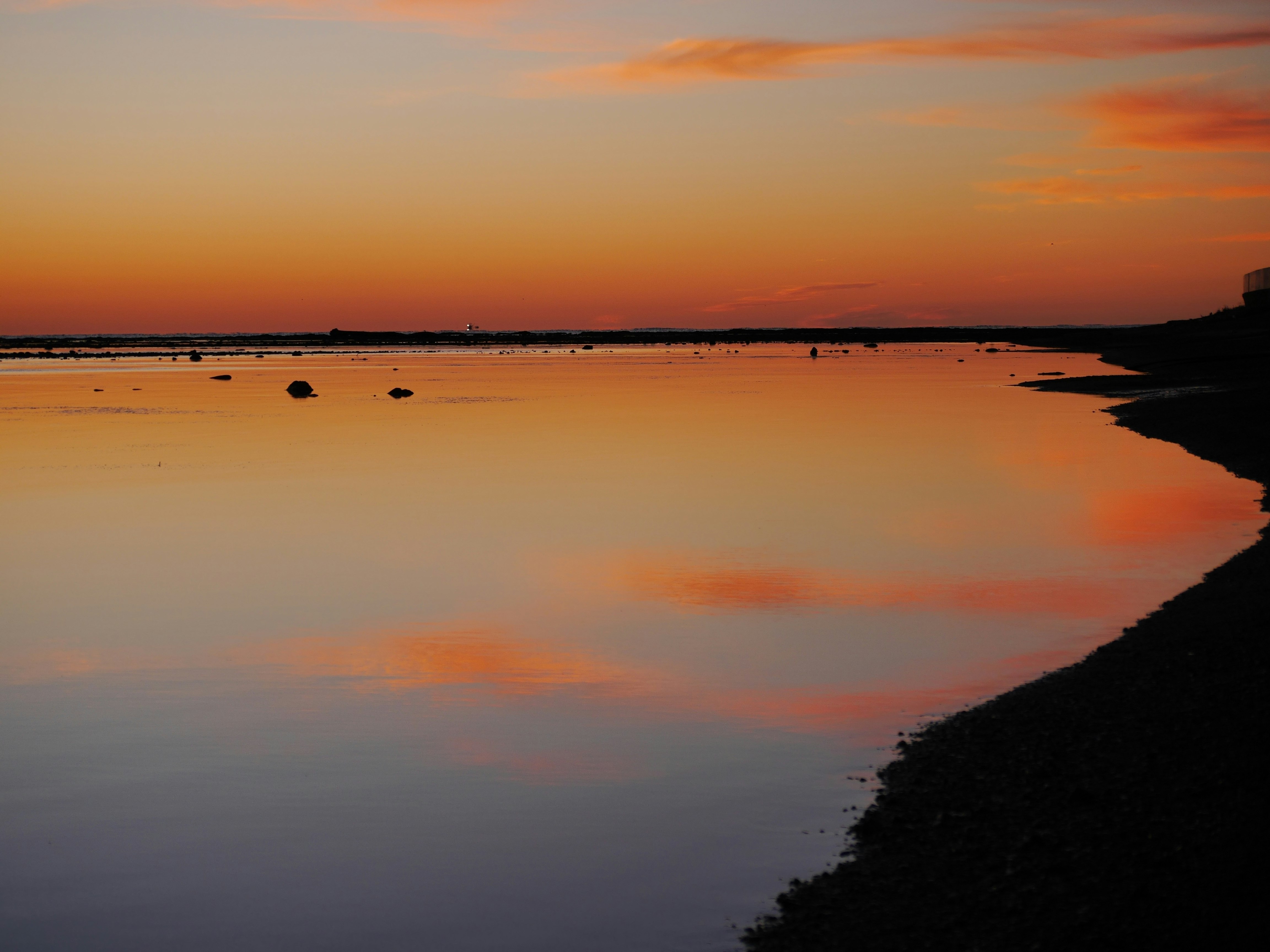 eau calme sur le littoral au coucher du soleil et horizon lumineux