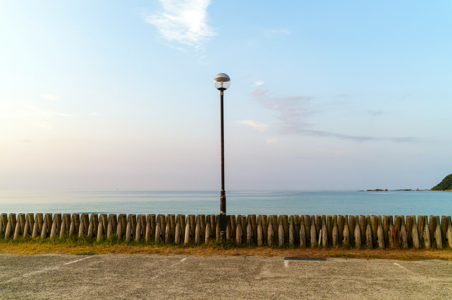Vista serena del mar con un farol y una barrera de madera