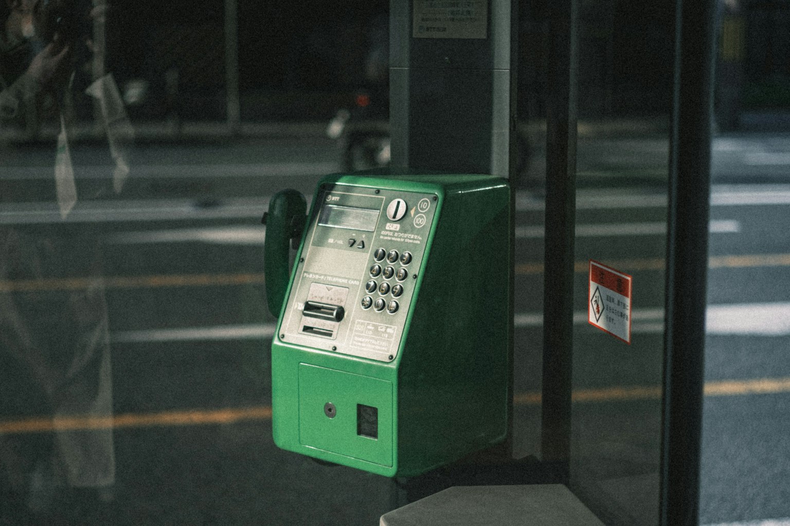 Una cabina telefonica pubblica verde situata all'angolo di una strada