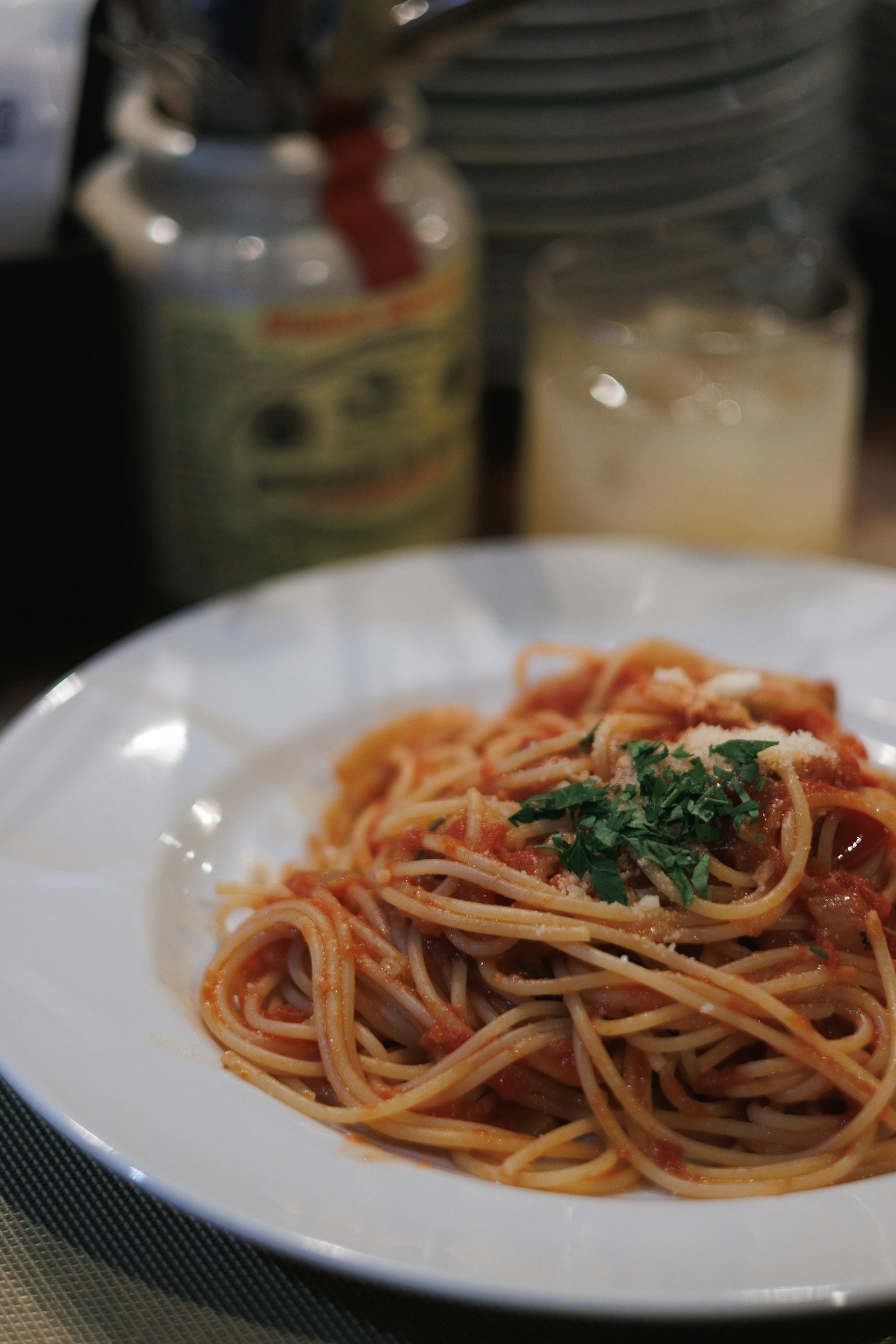 Spaghetti with tomato sauce topped with parsley on a white plate