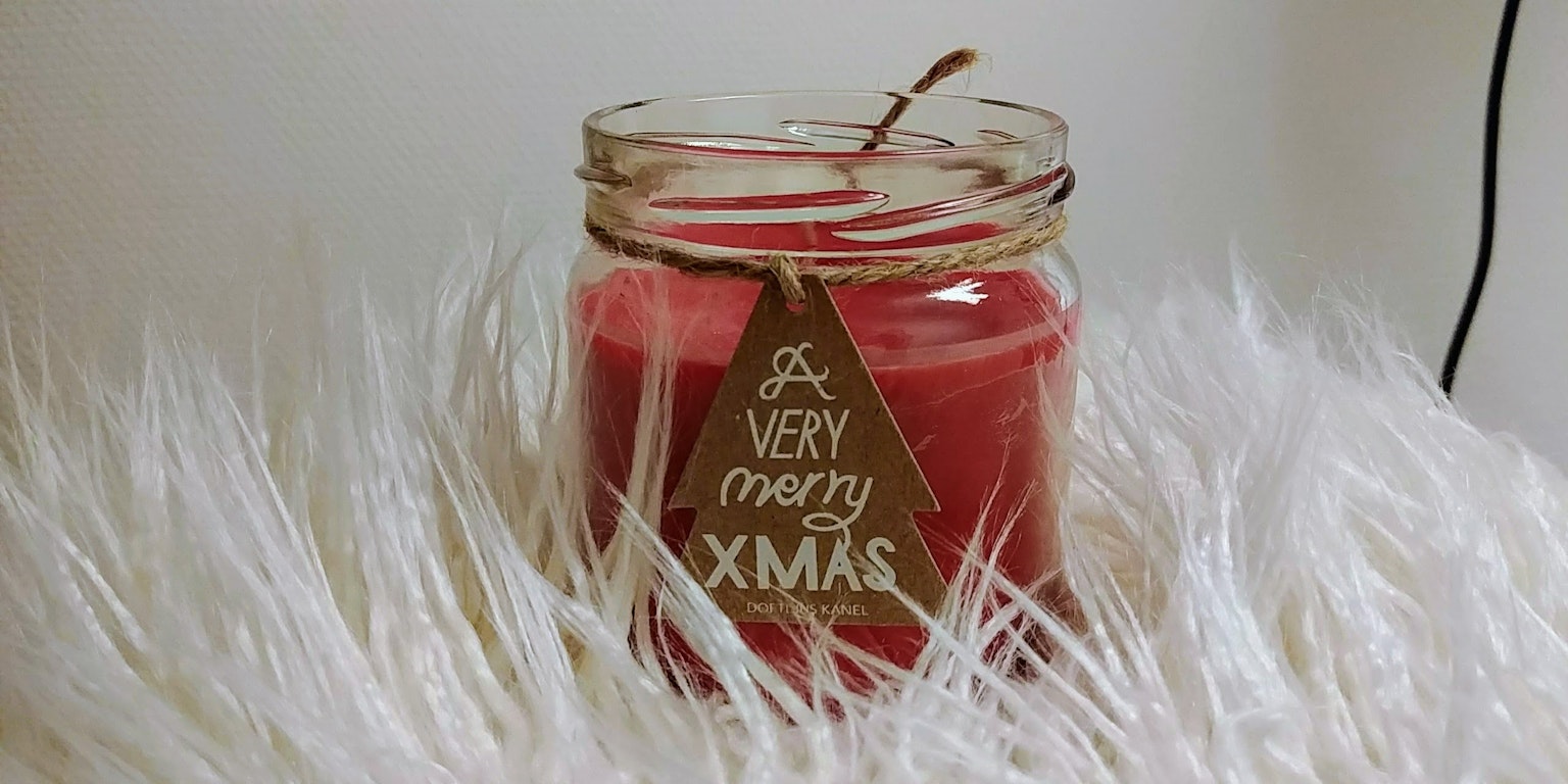 Red candle in a glass jar placed on fluffy white fur