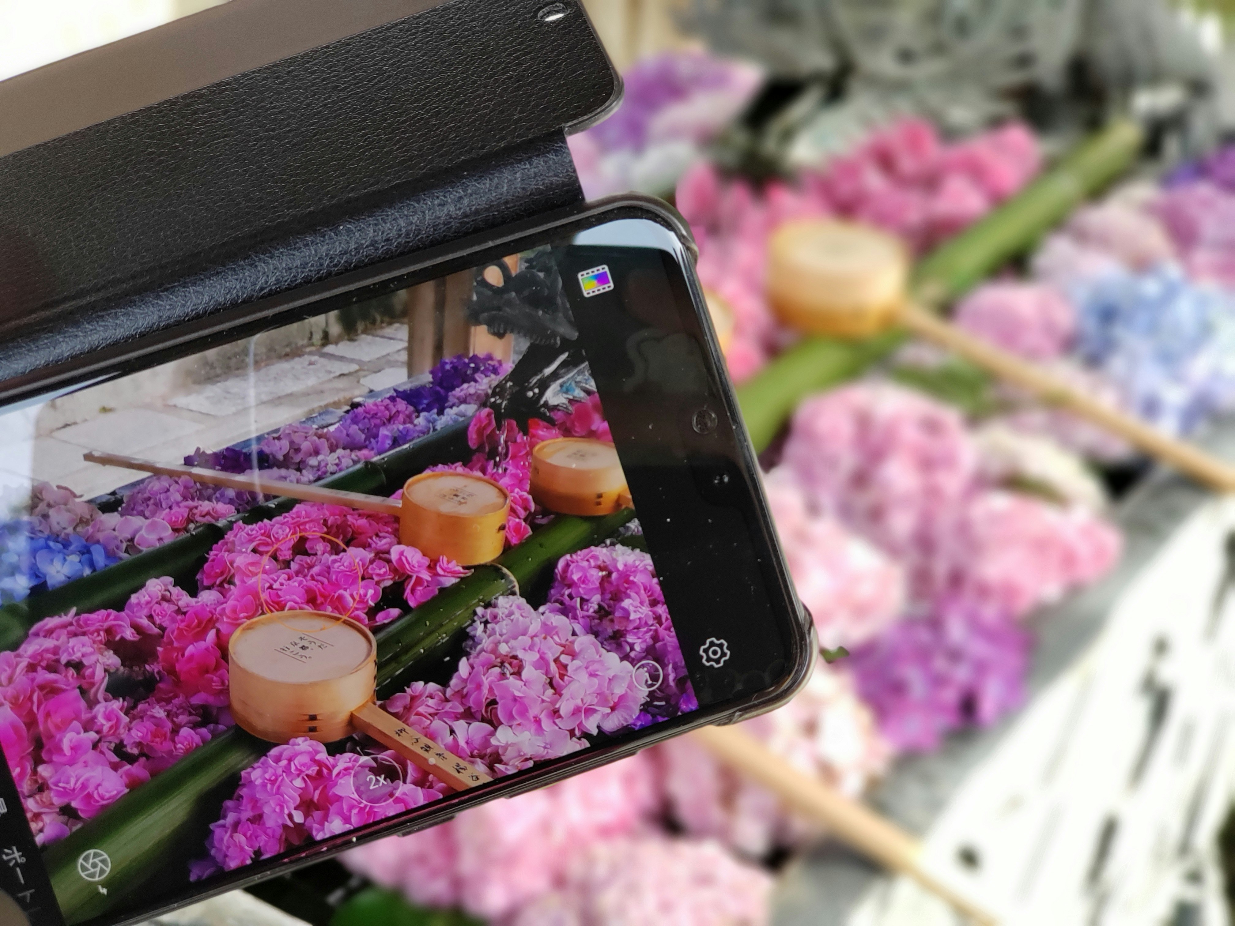 スマホ越しに並ぶ色鮮やかな花とキャンドルのギフト画像