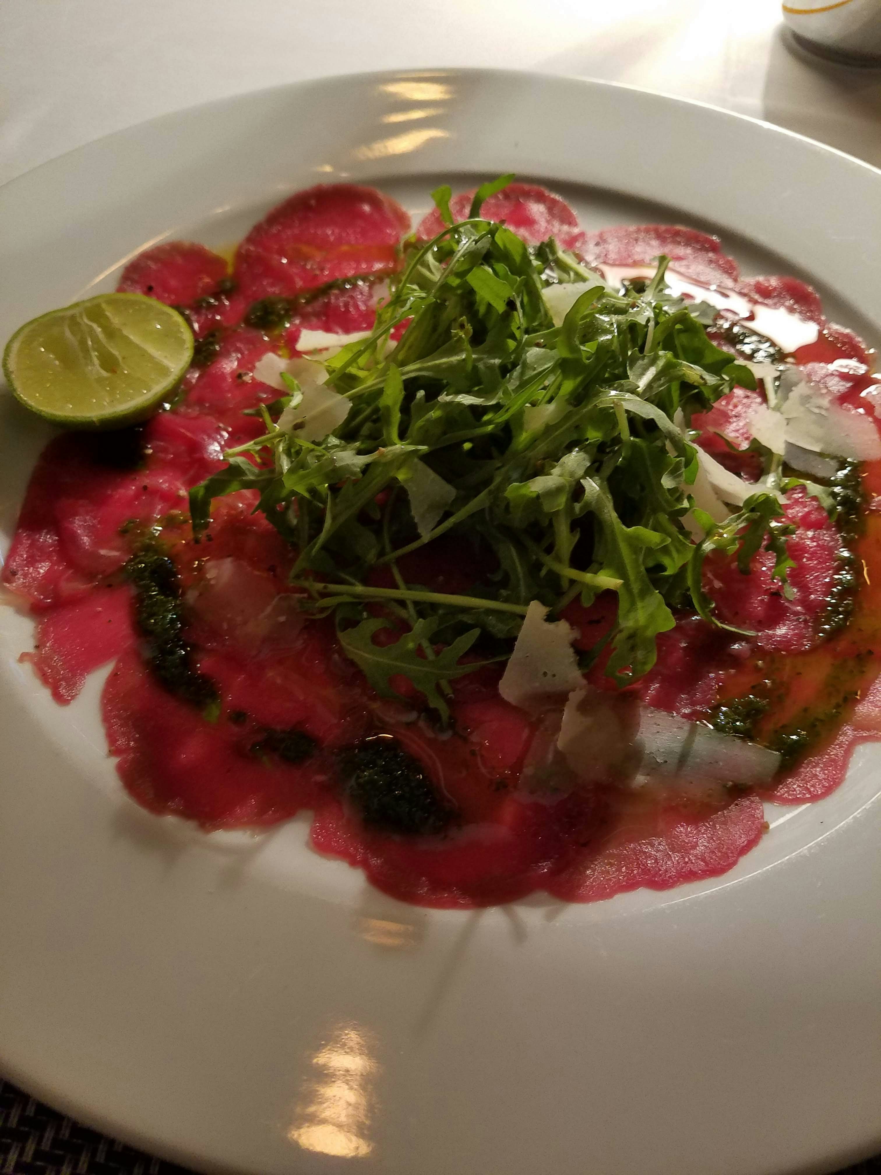 carpaccio rojo con lima y rúcula en un plato
