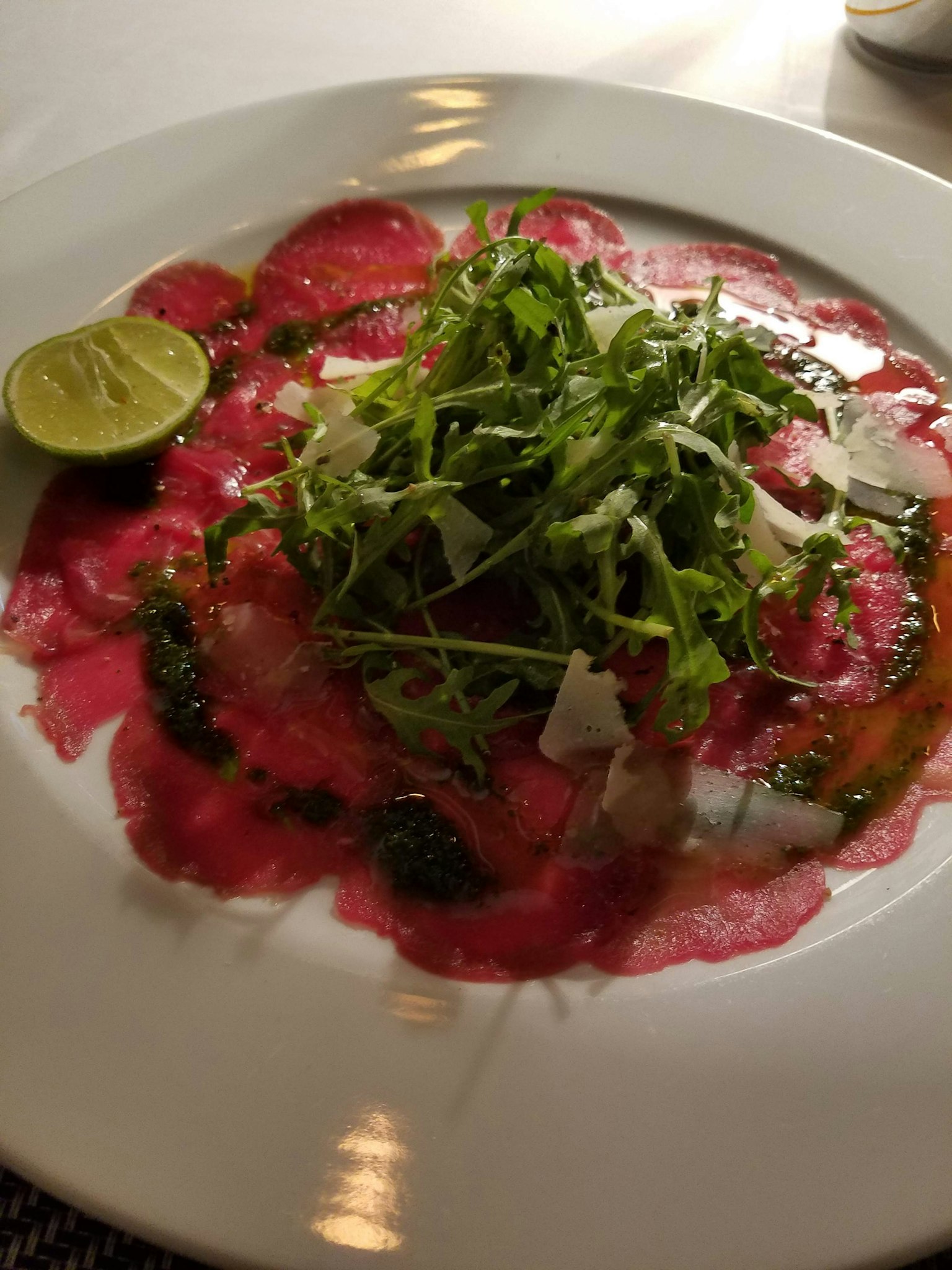 Piring daging tipis dengan arugula dan disajikan dengan jeruk nipis