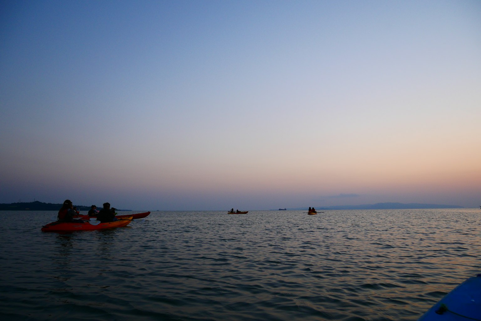 Silhouetten von Menschen, die bei Sonnenuntergang auf dem Meer Kajak fahren