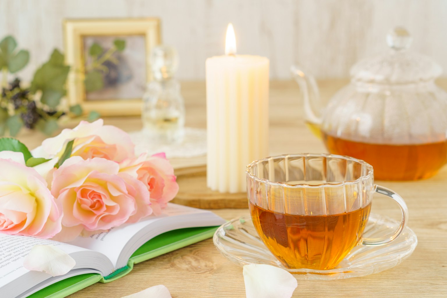 Une table accueillante avec une tasse de thé une bougie allumée une théière et des roses roses