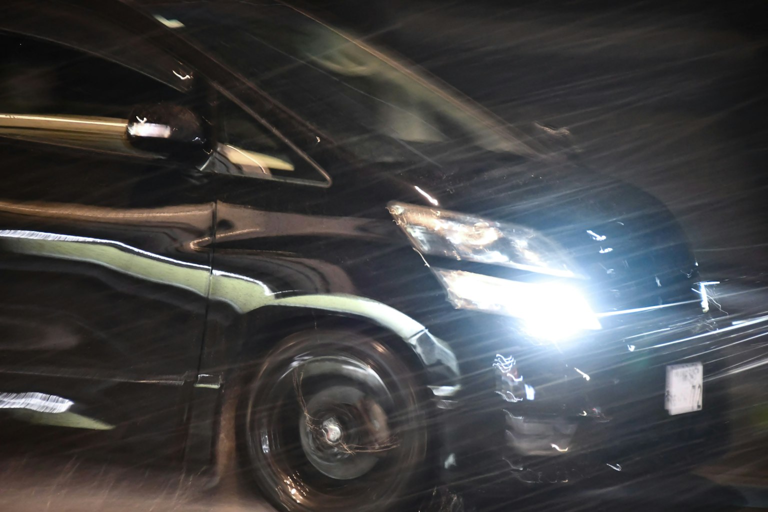 Một chiếc xe hơi đen mờ di chuyển qua khung cảnh đêm