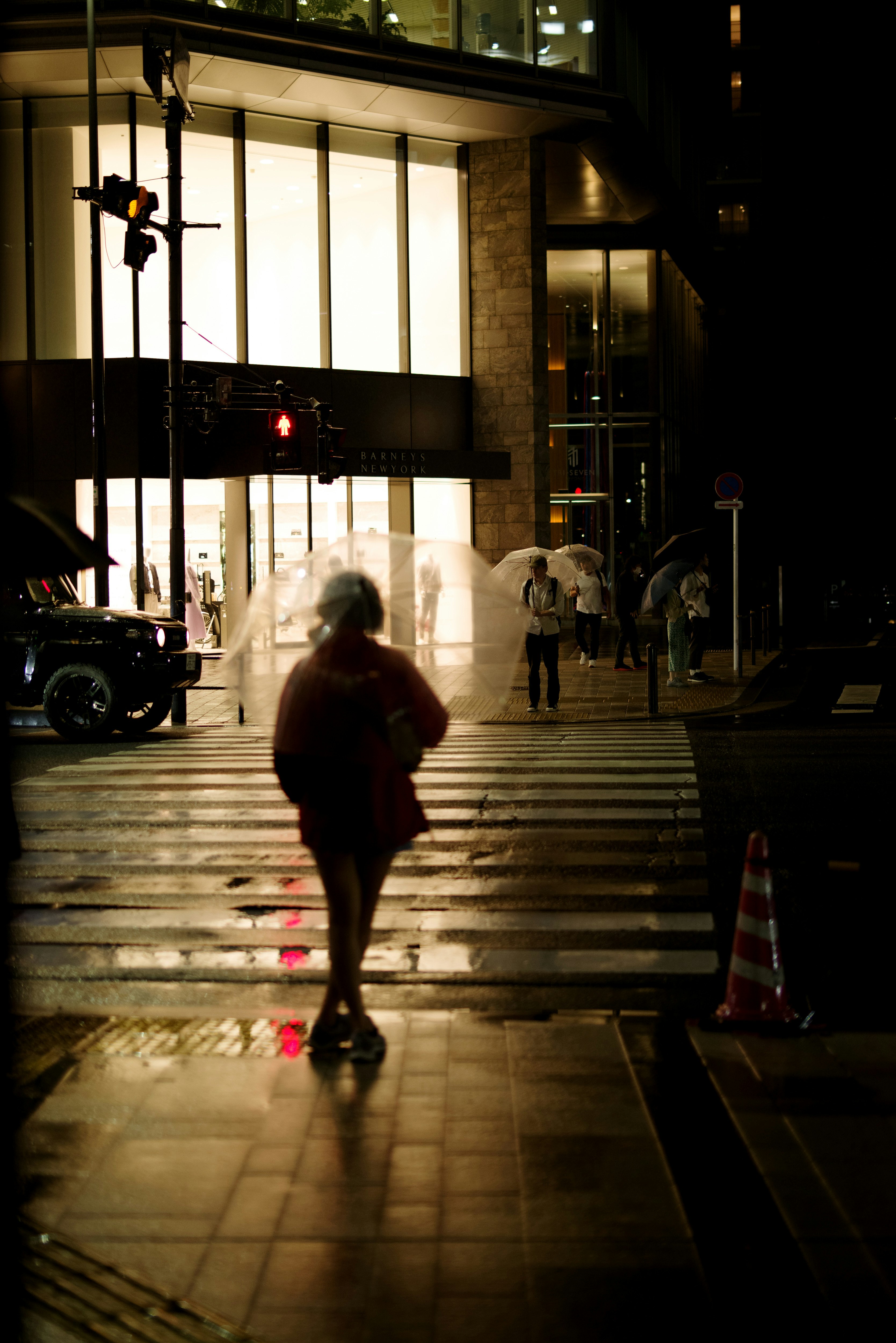 雨の東京の街角で横断歩道を歩く人々の夜景