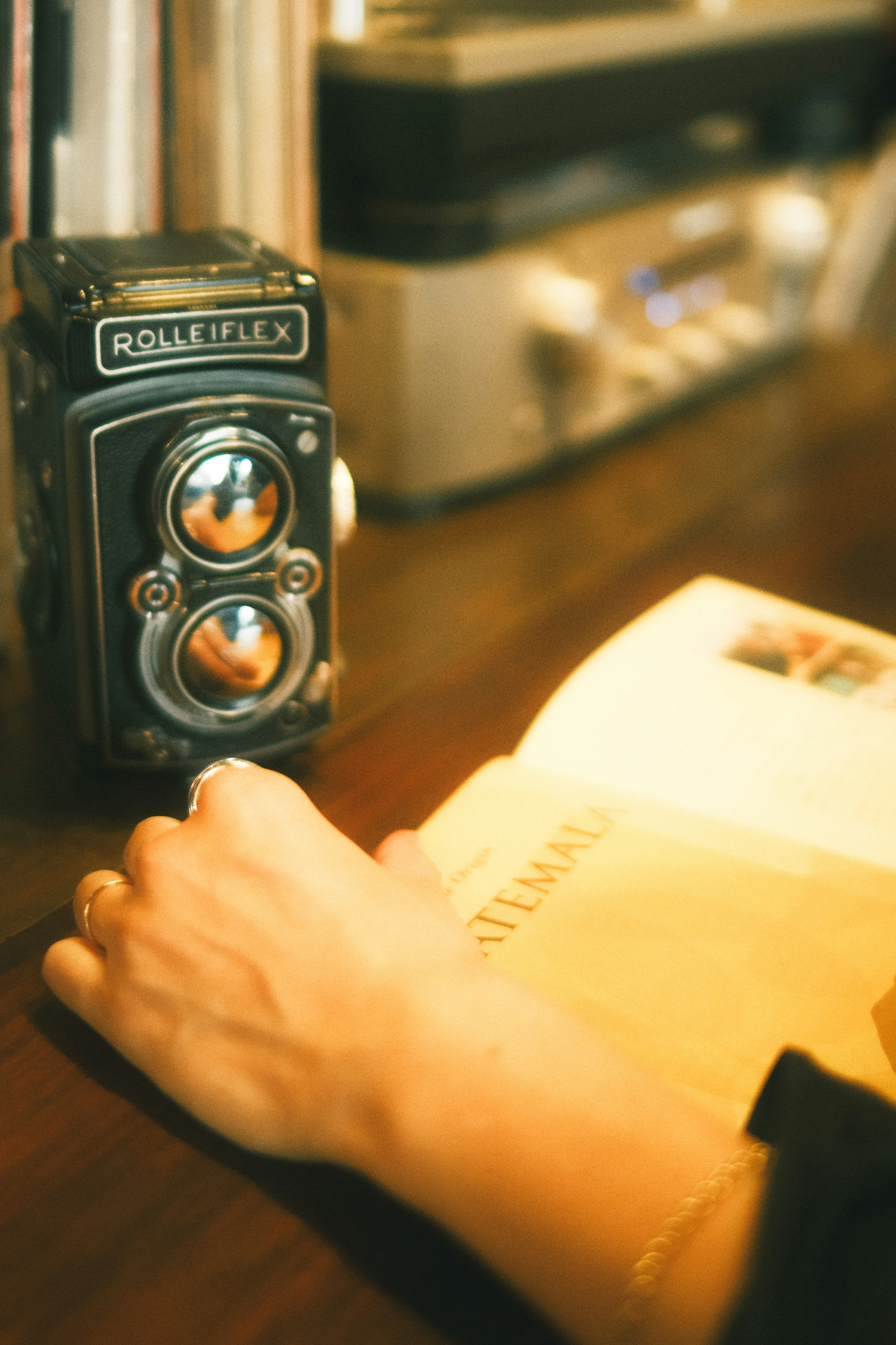 手に持ったフィルムカメラとレトロな室内の机上風景