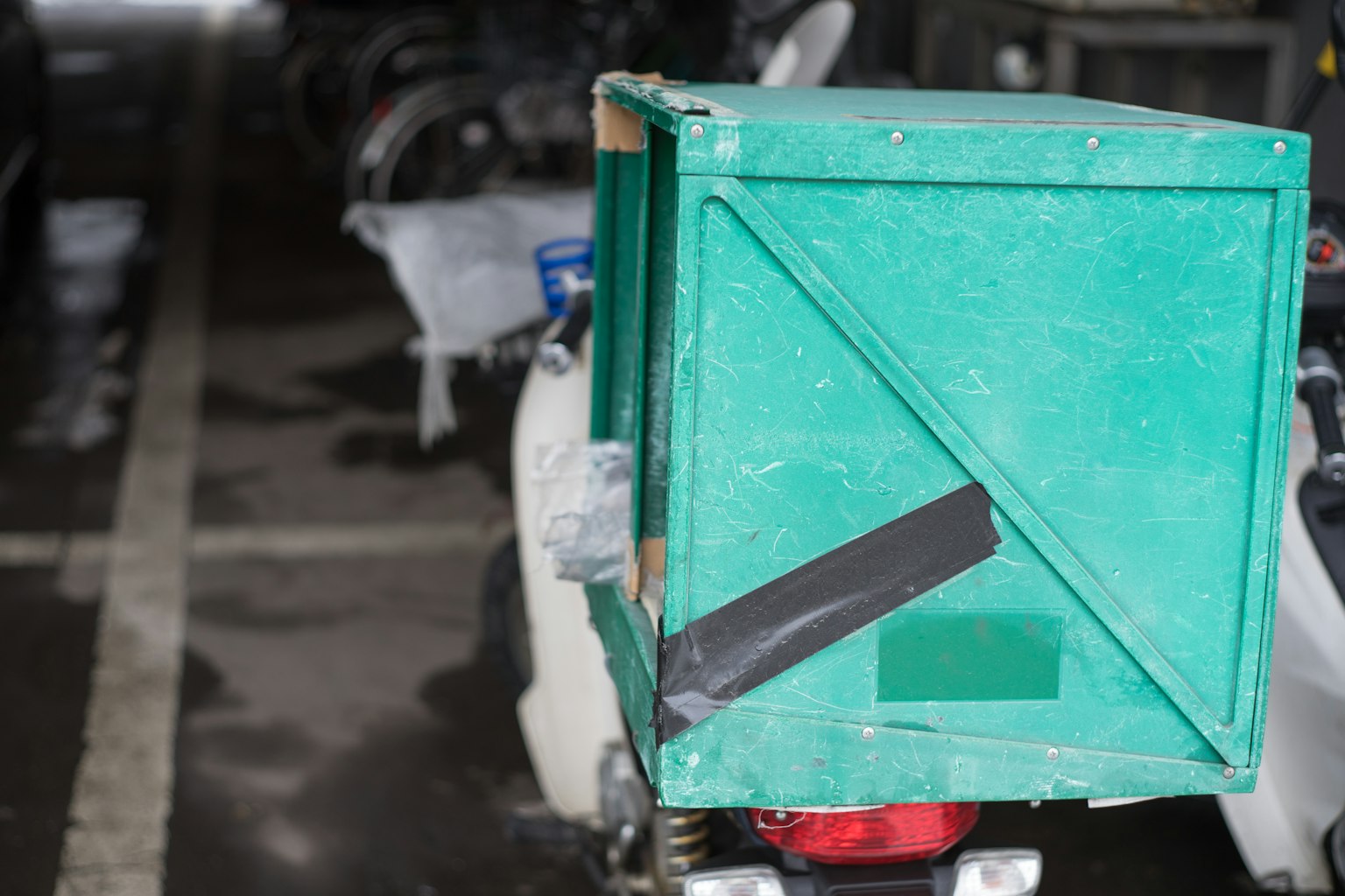 Một hộp giao hàng màu xanh gắn ở phía sau xe máy