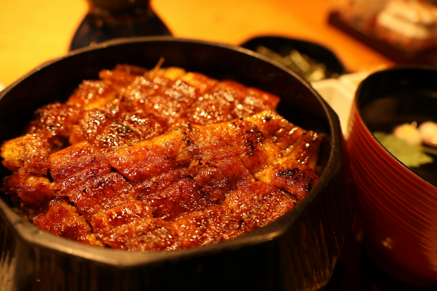 美味的鰻魚飯放在黑色碗中，旁邊有味噌湯