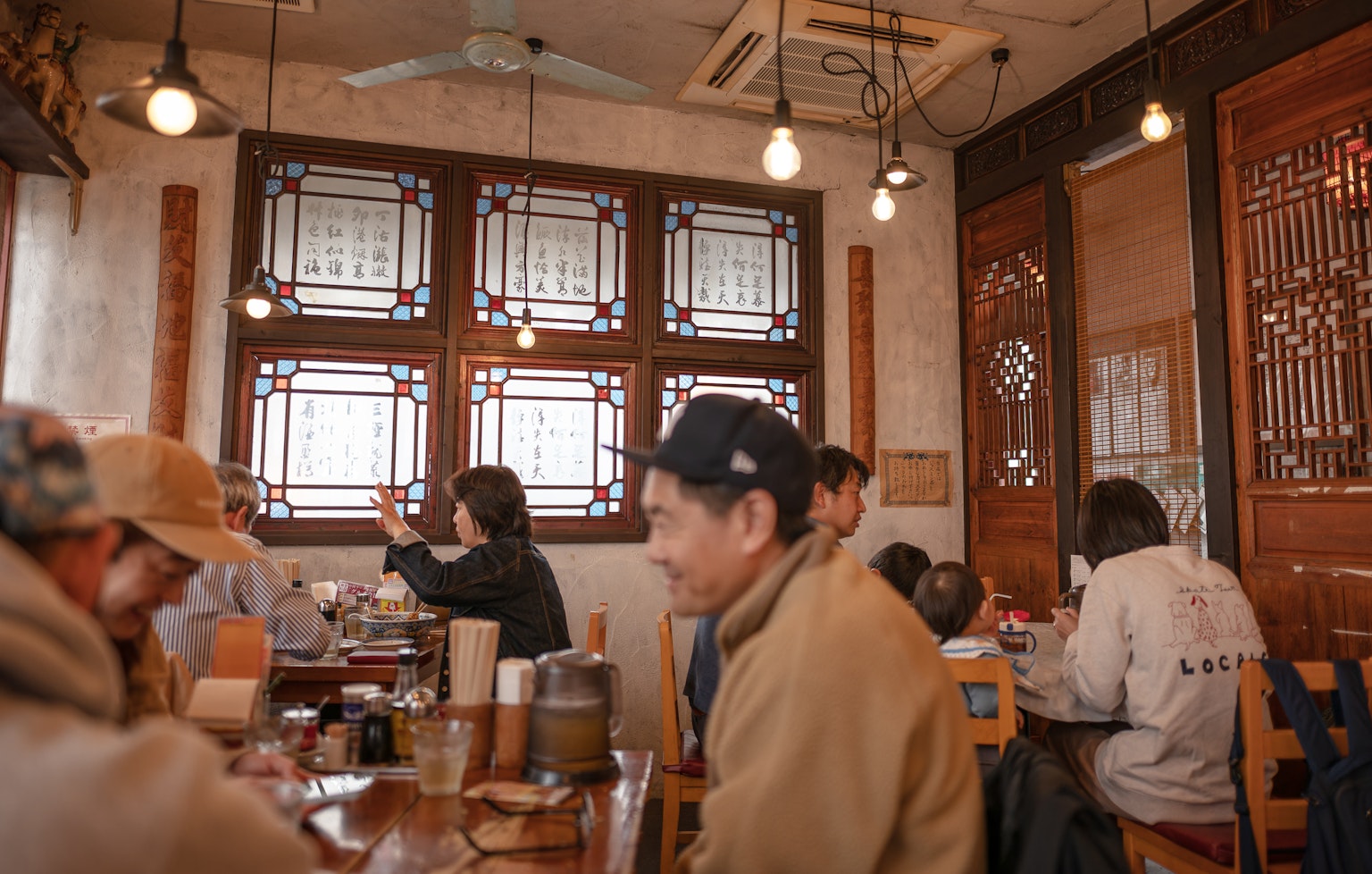 ภายในร้านกาแฟมีหน้าต่างกระจกสีและผู้คนกำลังผ่อนคลายในบรรยากาศอบอุ่น
