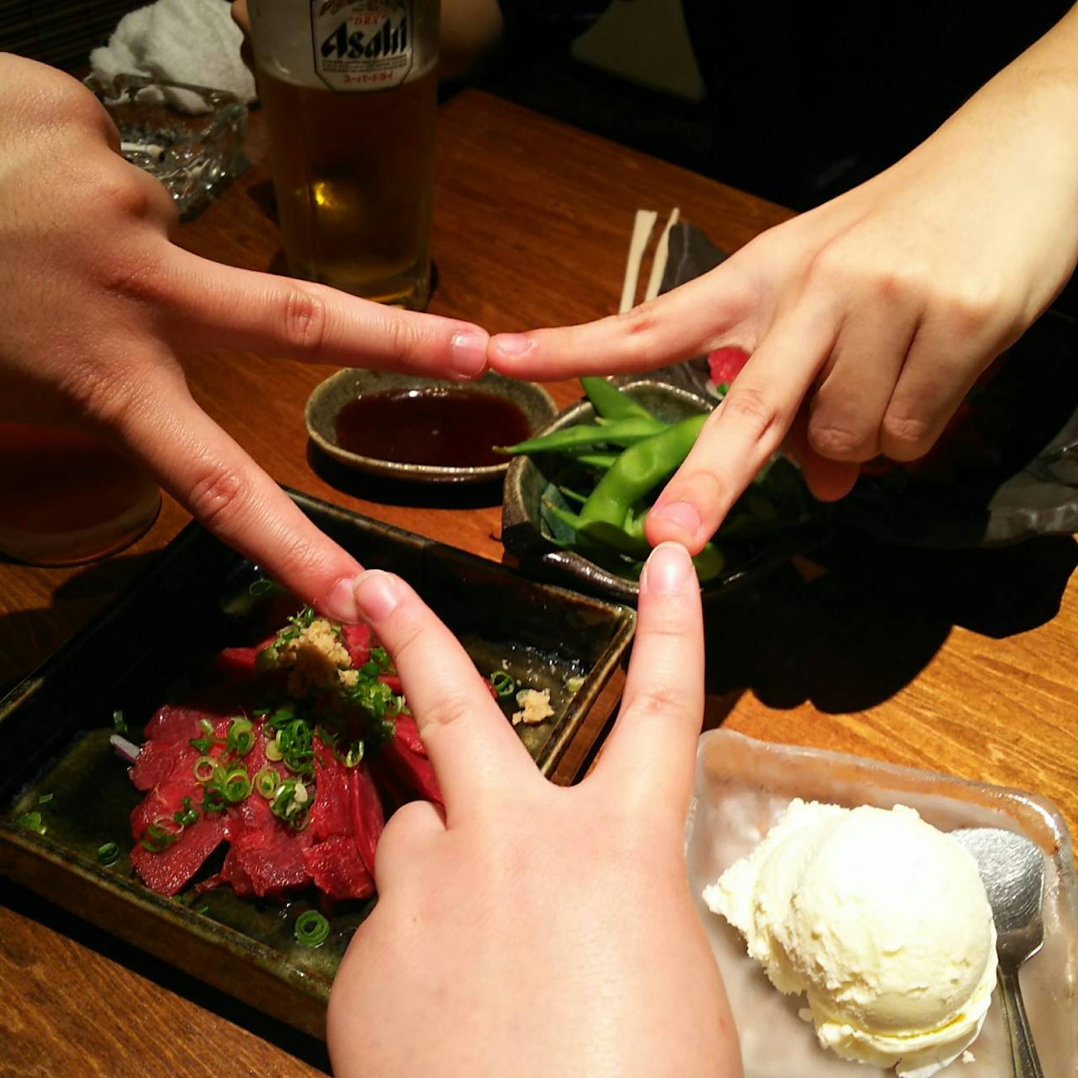 Two hands forming a V shape around a meal featuring delicious meat dish and ice cream
