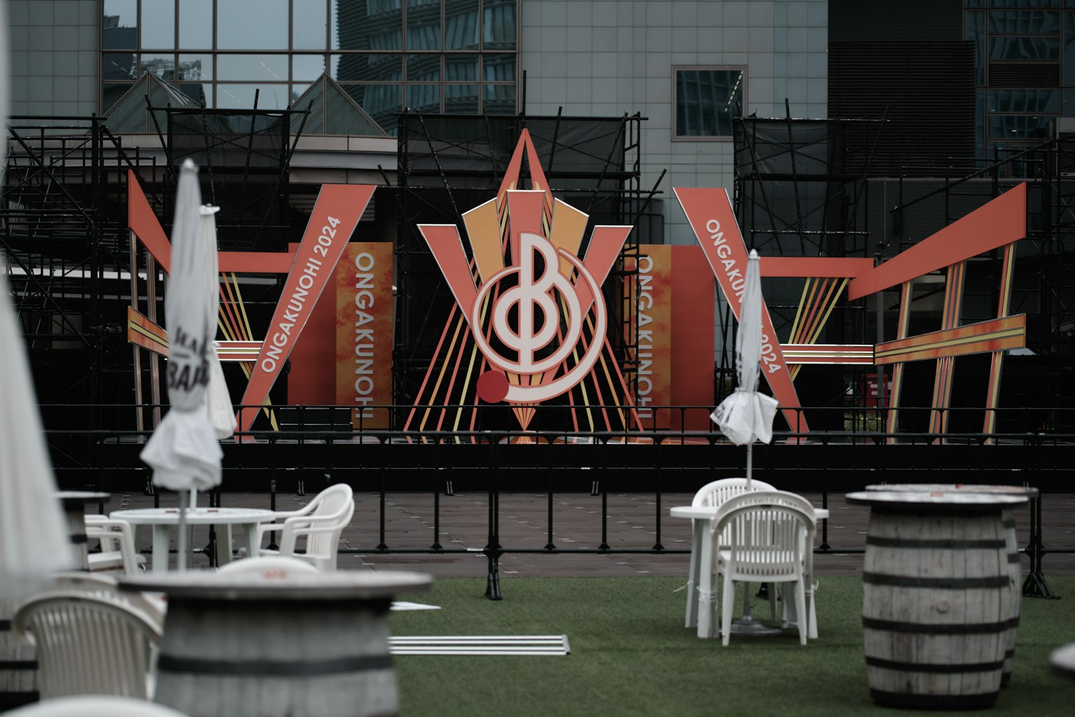 การจัดเวทีสำหรับงานเพลงที่มีการตกแต่งสีส้มและเก้าอี้สีขาว