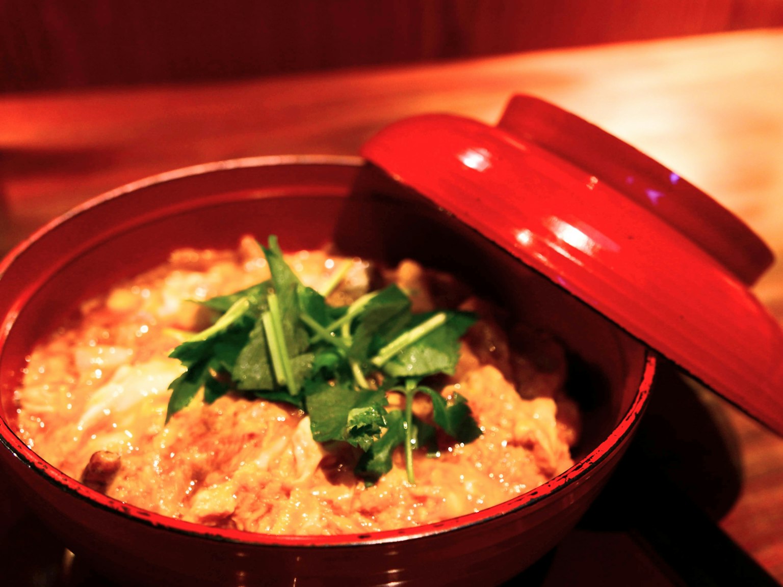ชามสีแดงที่เต็มไปด้วยจานไข่และไก่ที่ประดับด้วยสมุนไพร