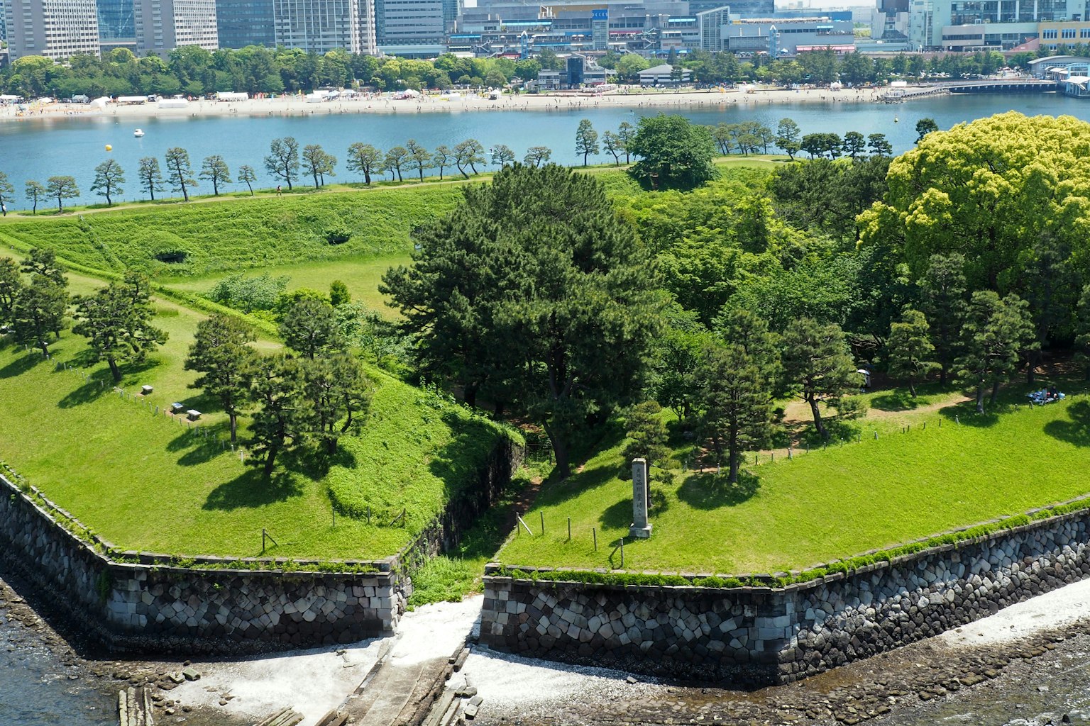 Üppiger grüner Park mit Blick auf das Wasser und historischen Steinmauern