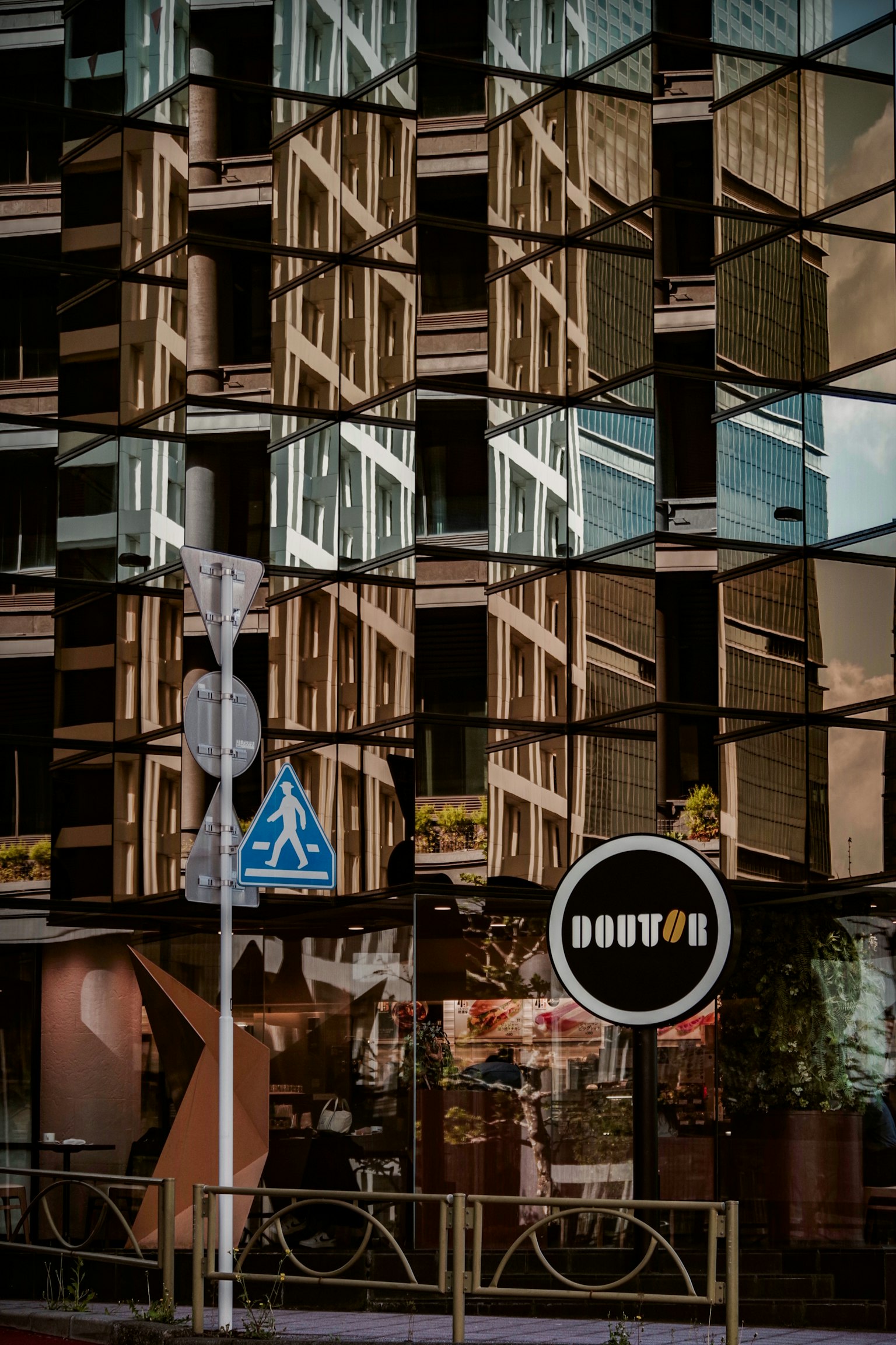 Façade d'un bâtiment moderne avec des reflets en verre et un panneau de boutique de beignets