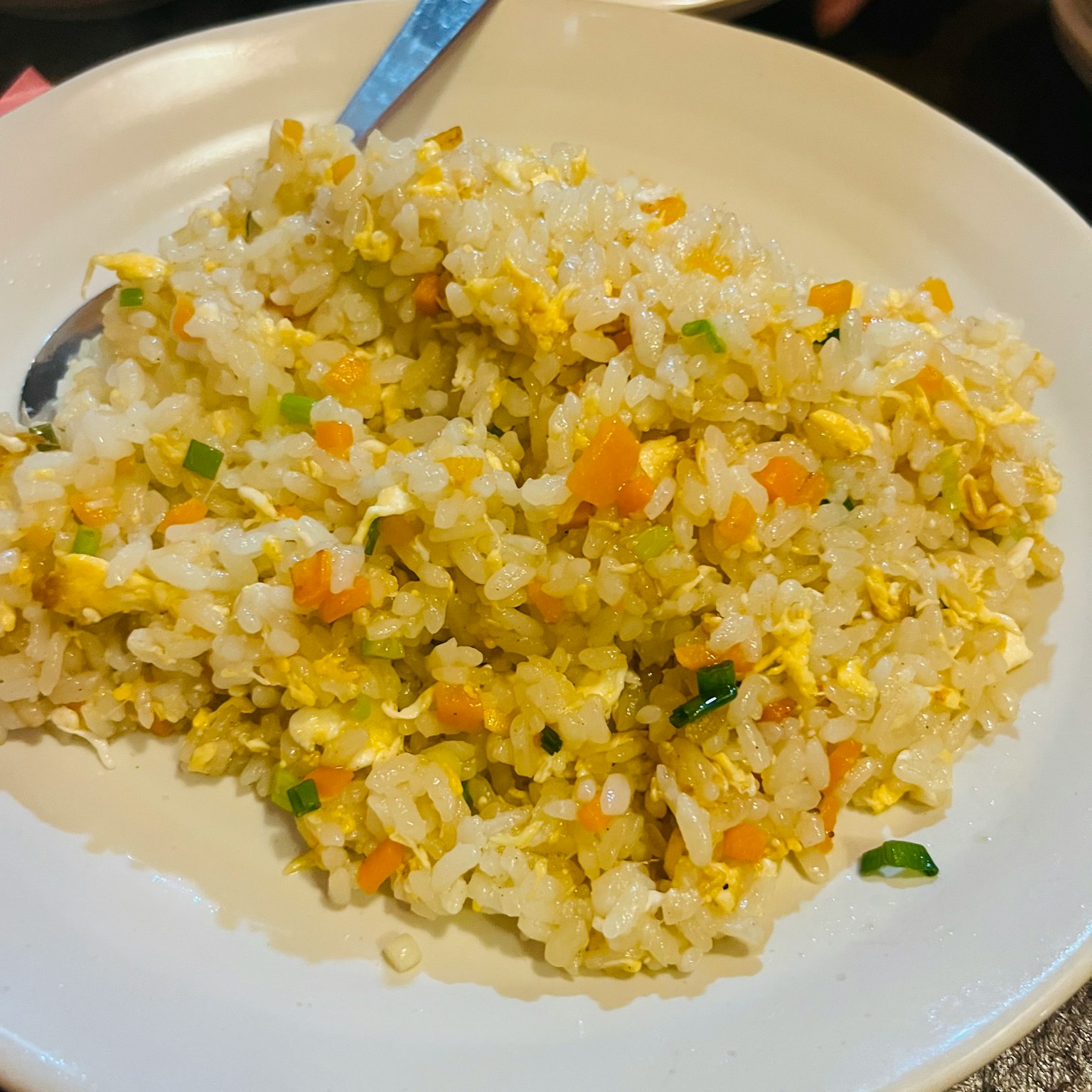 Plato de arroz frito dorado con cebollas verdes y zanahorias ralladas