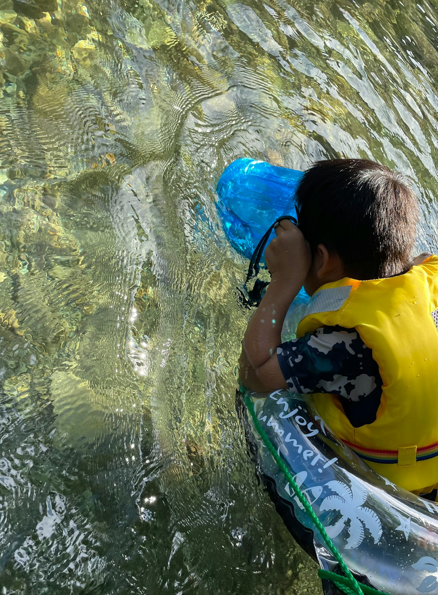 Bambino che usa un boccaglio blu per osservare sott'acqua