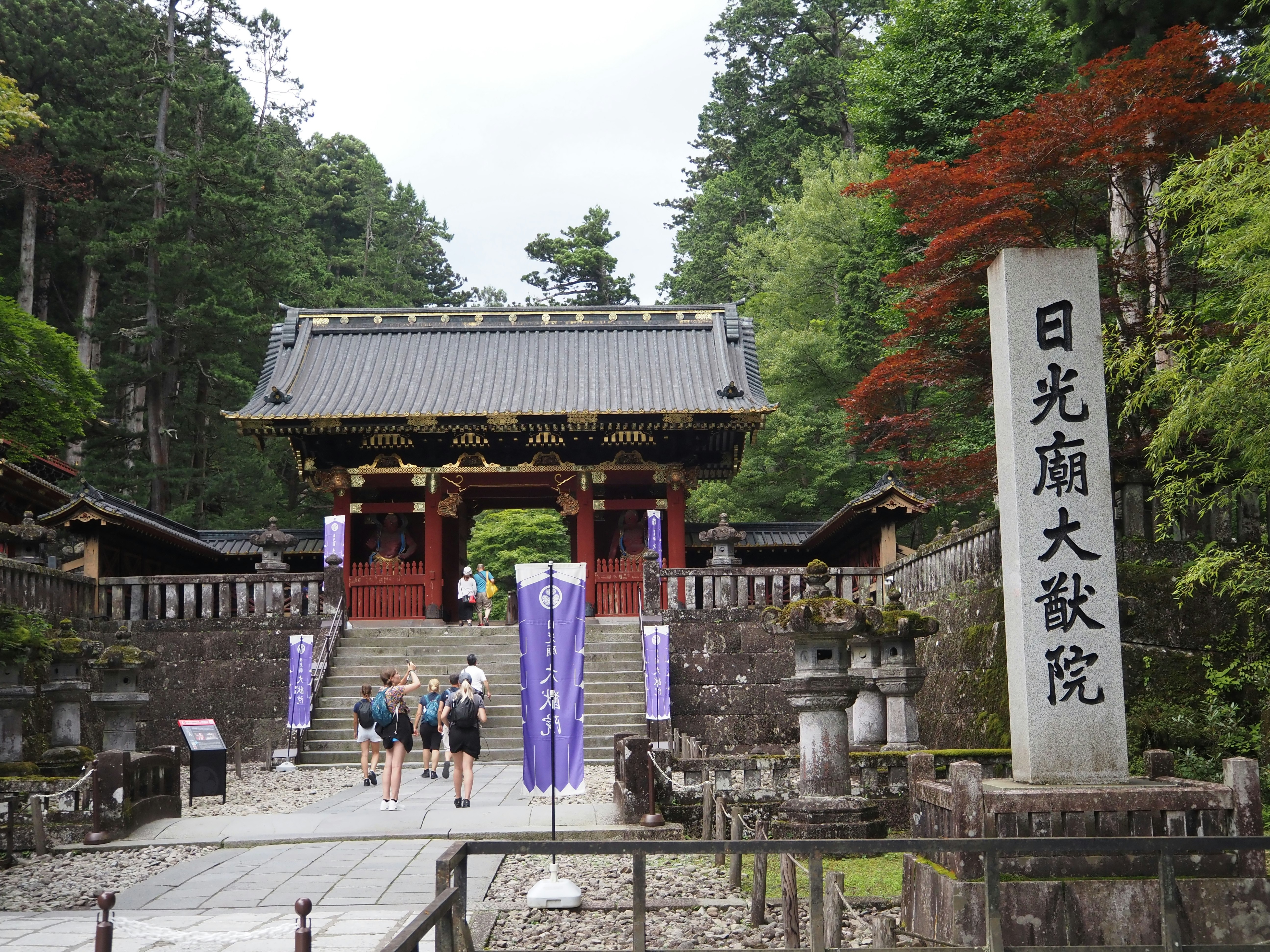 石畳の参道と門、日光願大欲院の幟が並ぶ寺院の景色