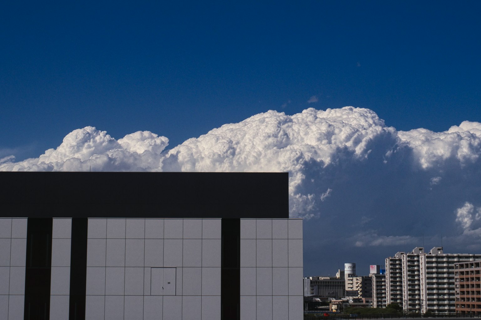 Una vista di un edificio bianco con linee verticali nere contro uno sfondo di cielo blu e nuvole bianche e soffici