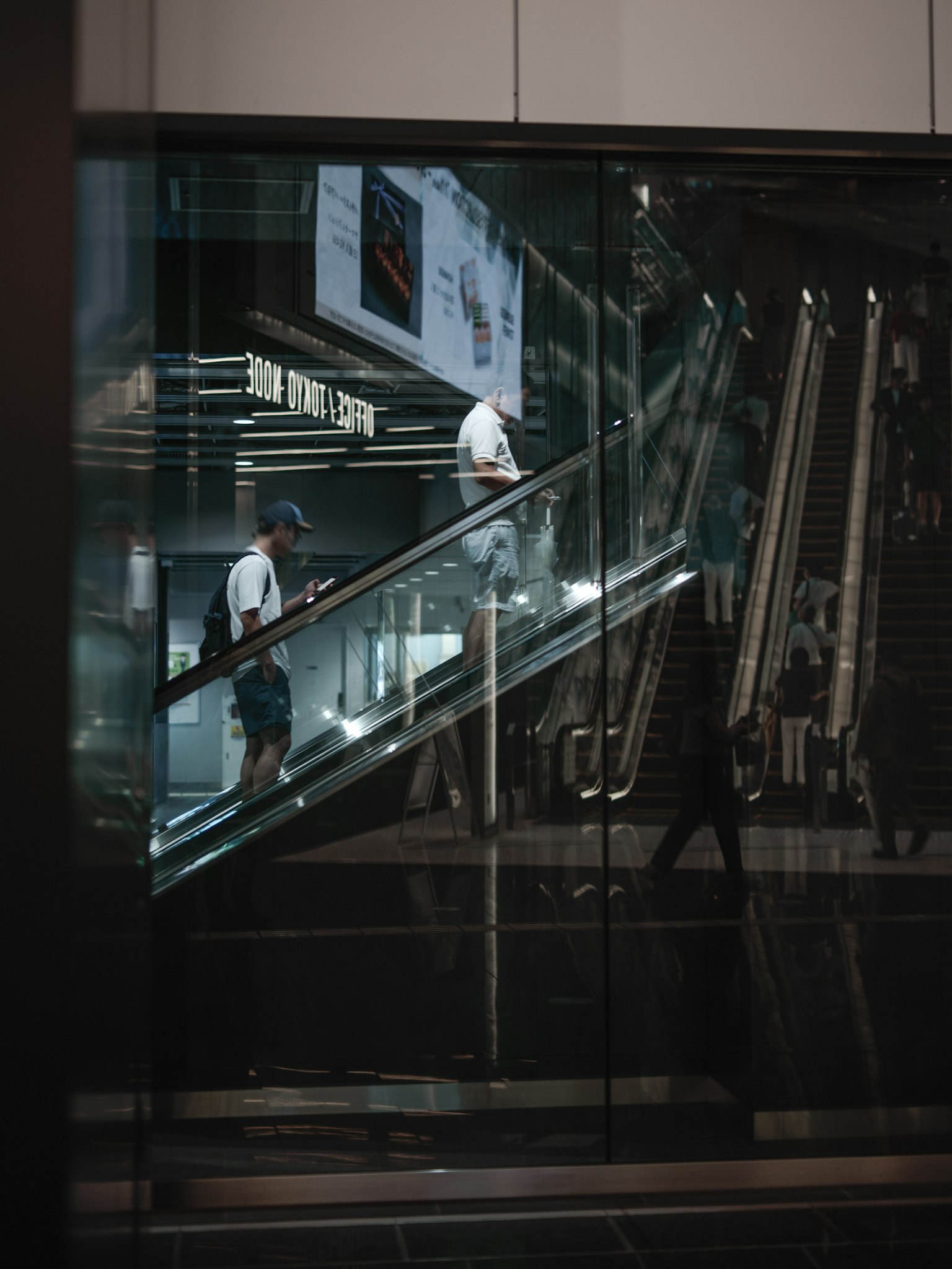 Phản chiếu của một người trên thang cuốn kính với quảng cáo