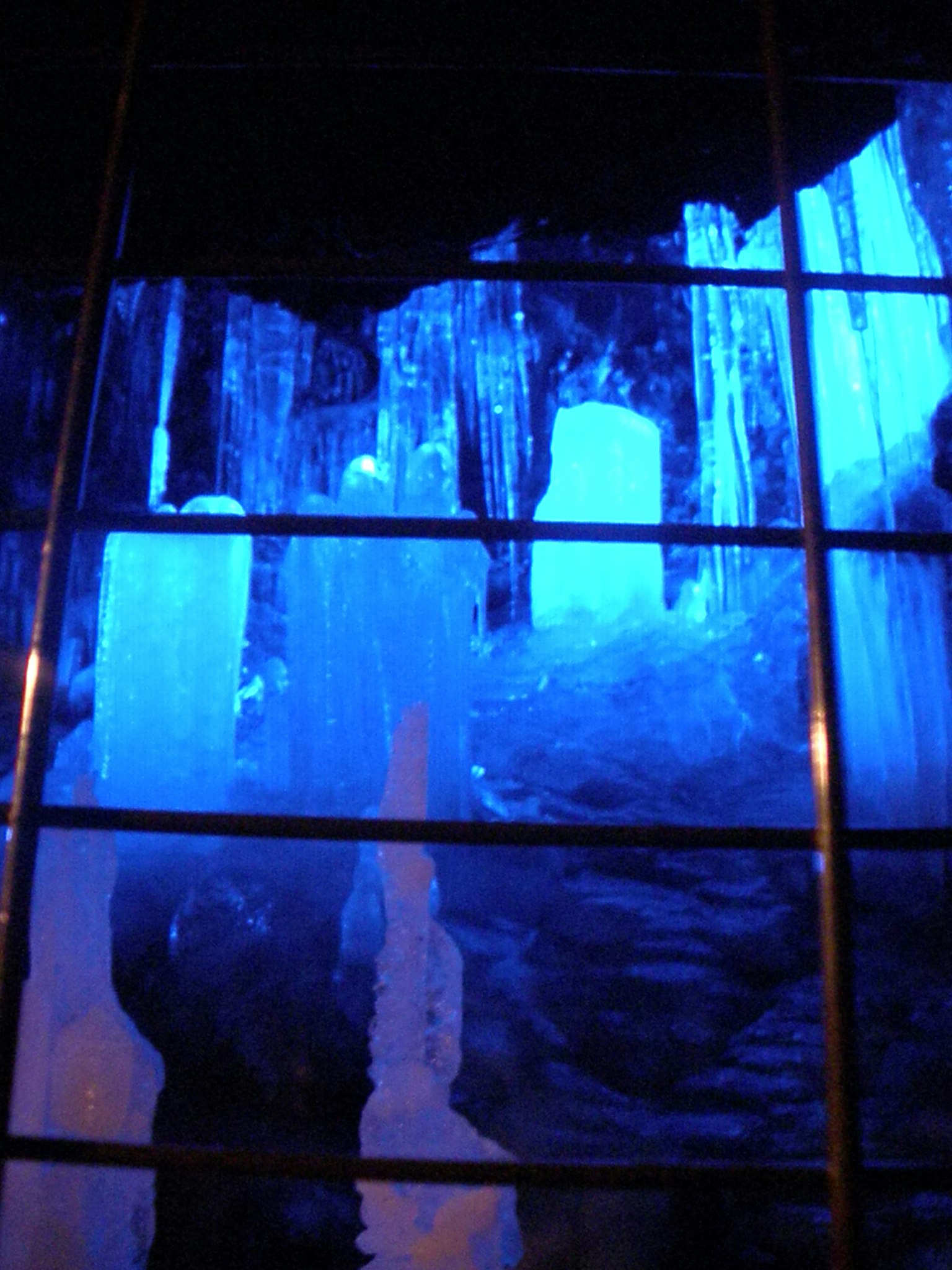 Intérieur d'une grotte avec des colonnes de glace éclairées par une lumière bleue