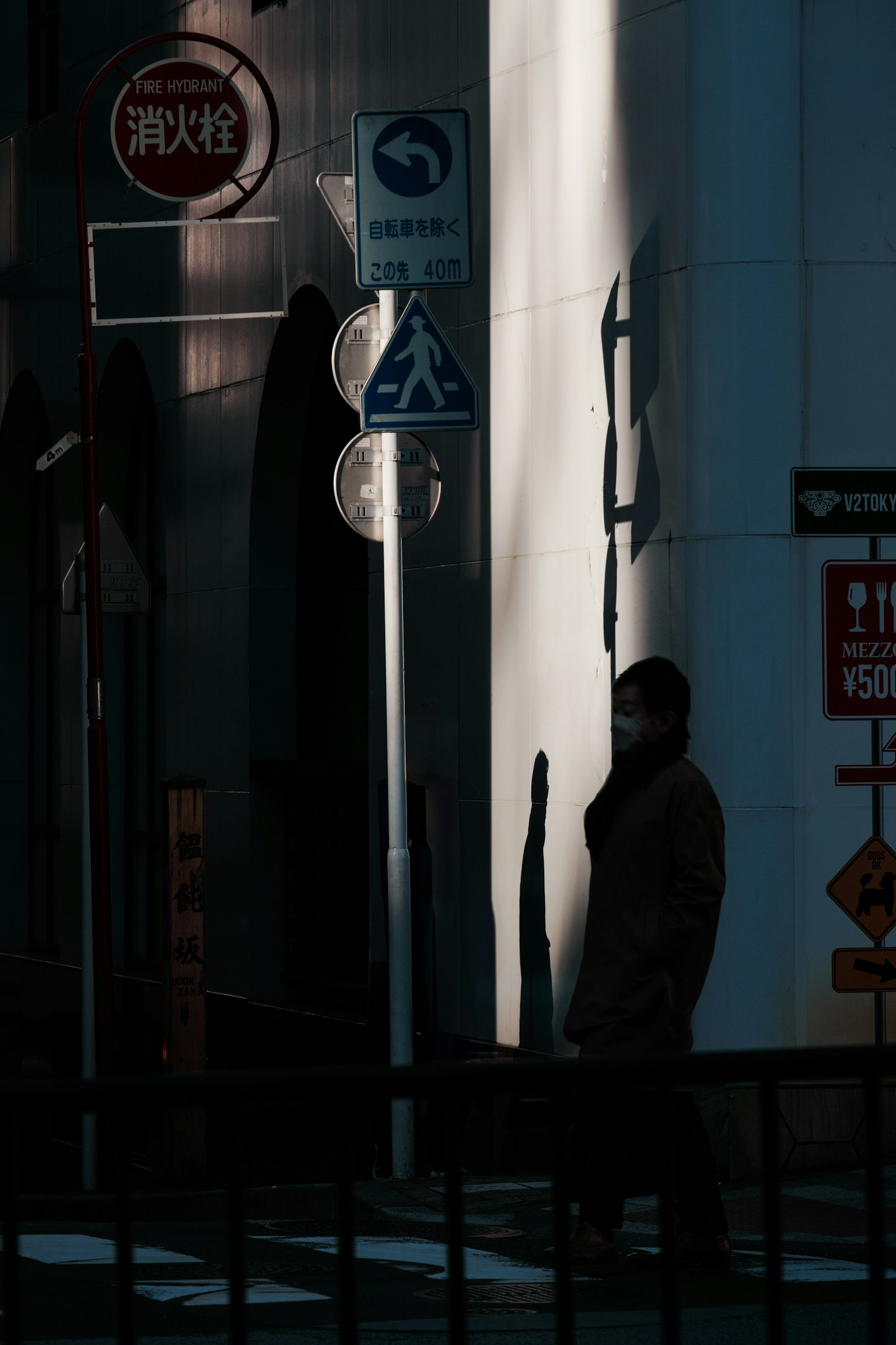 薄暗い通りで立つ人影と街の標識