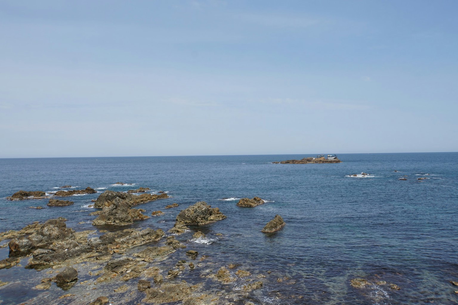 Laut biru tenang dengan garis pantai berbatu