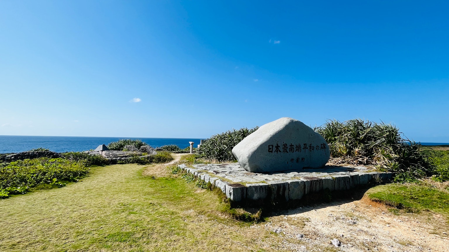 Grande monumento di pietra vicino al mare con erba verde