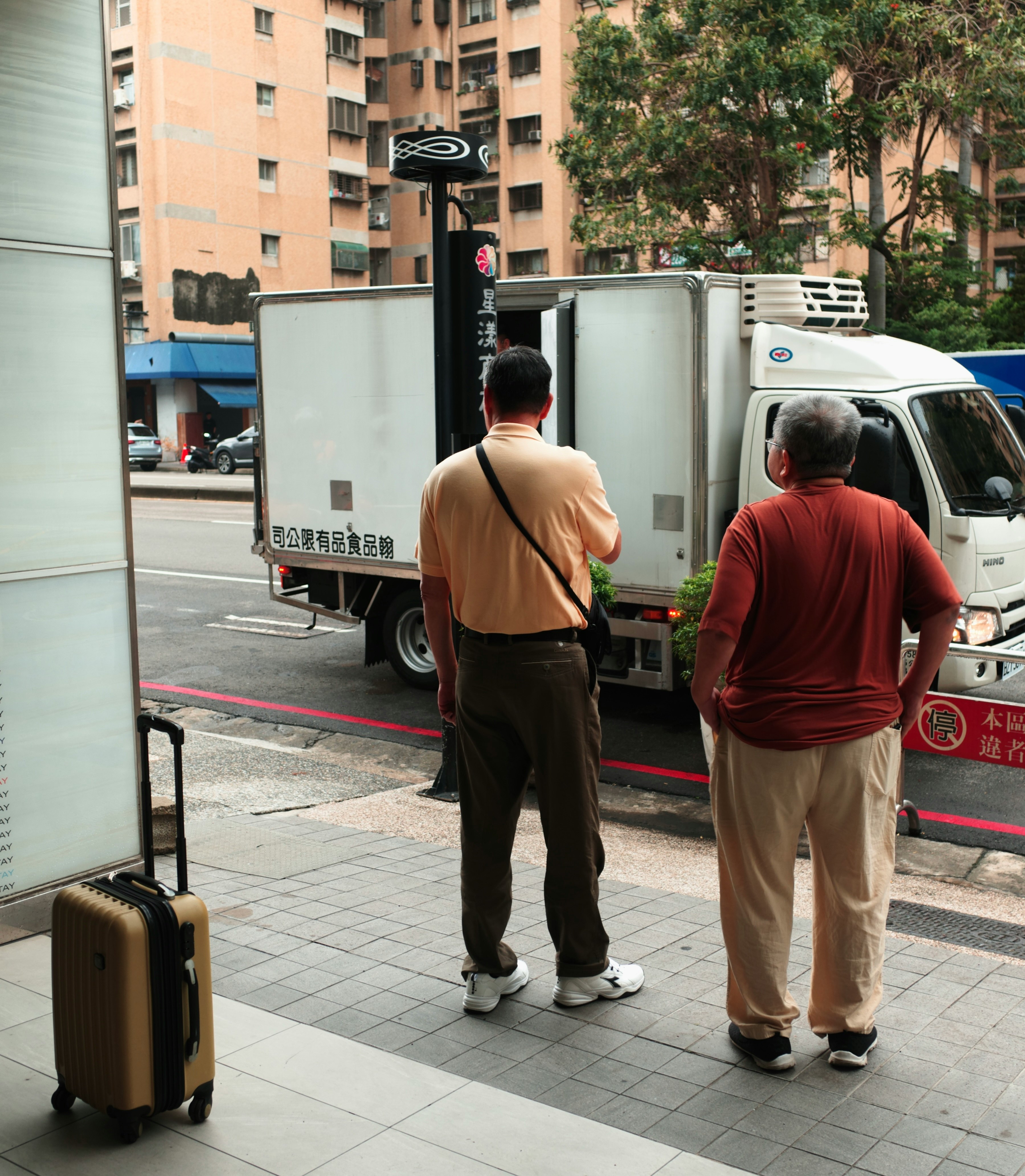 路上で荷物を持つ人と配送トラックのある街角
