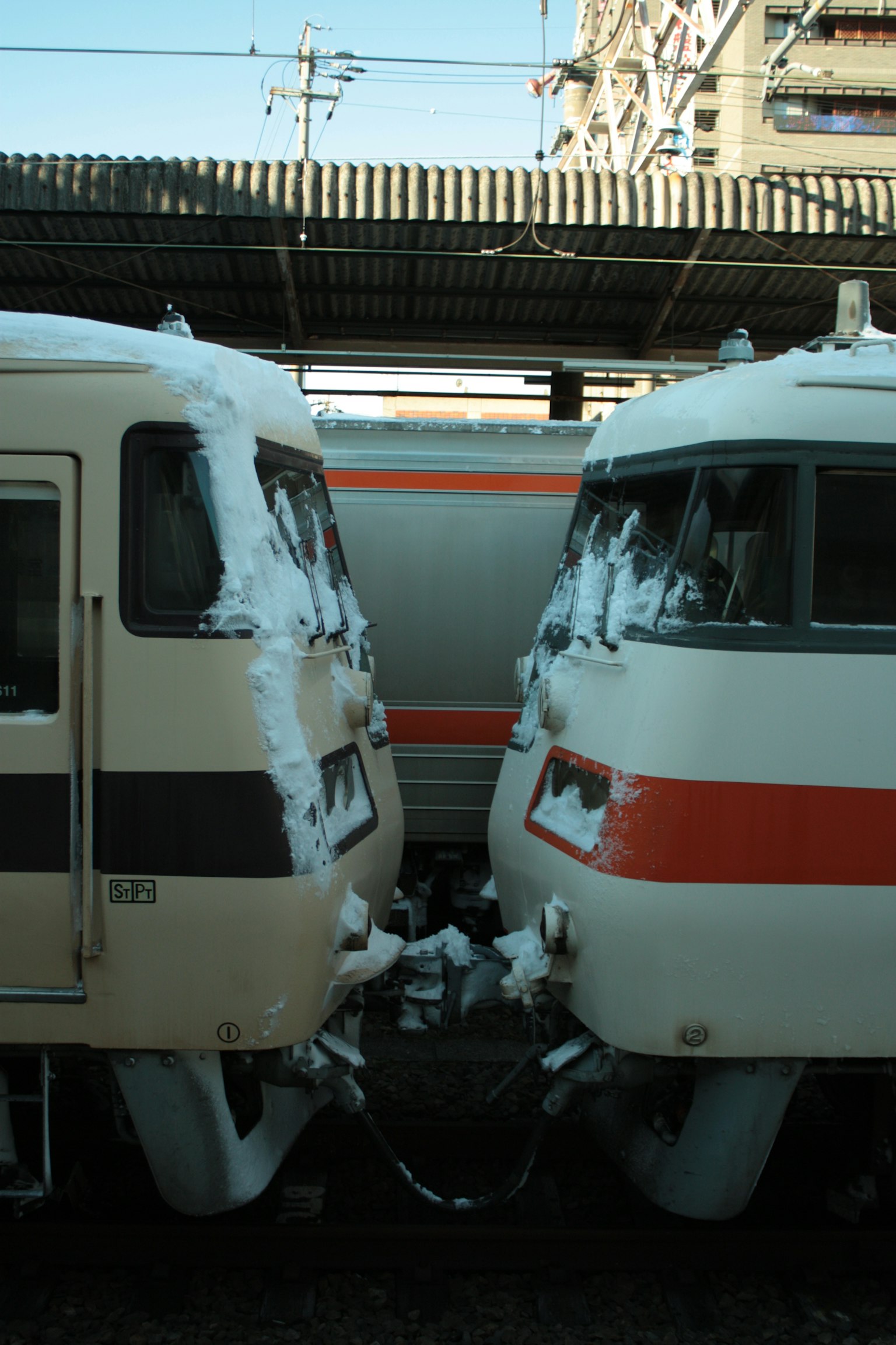Two trains covered in snow facing each other at a station