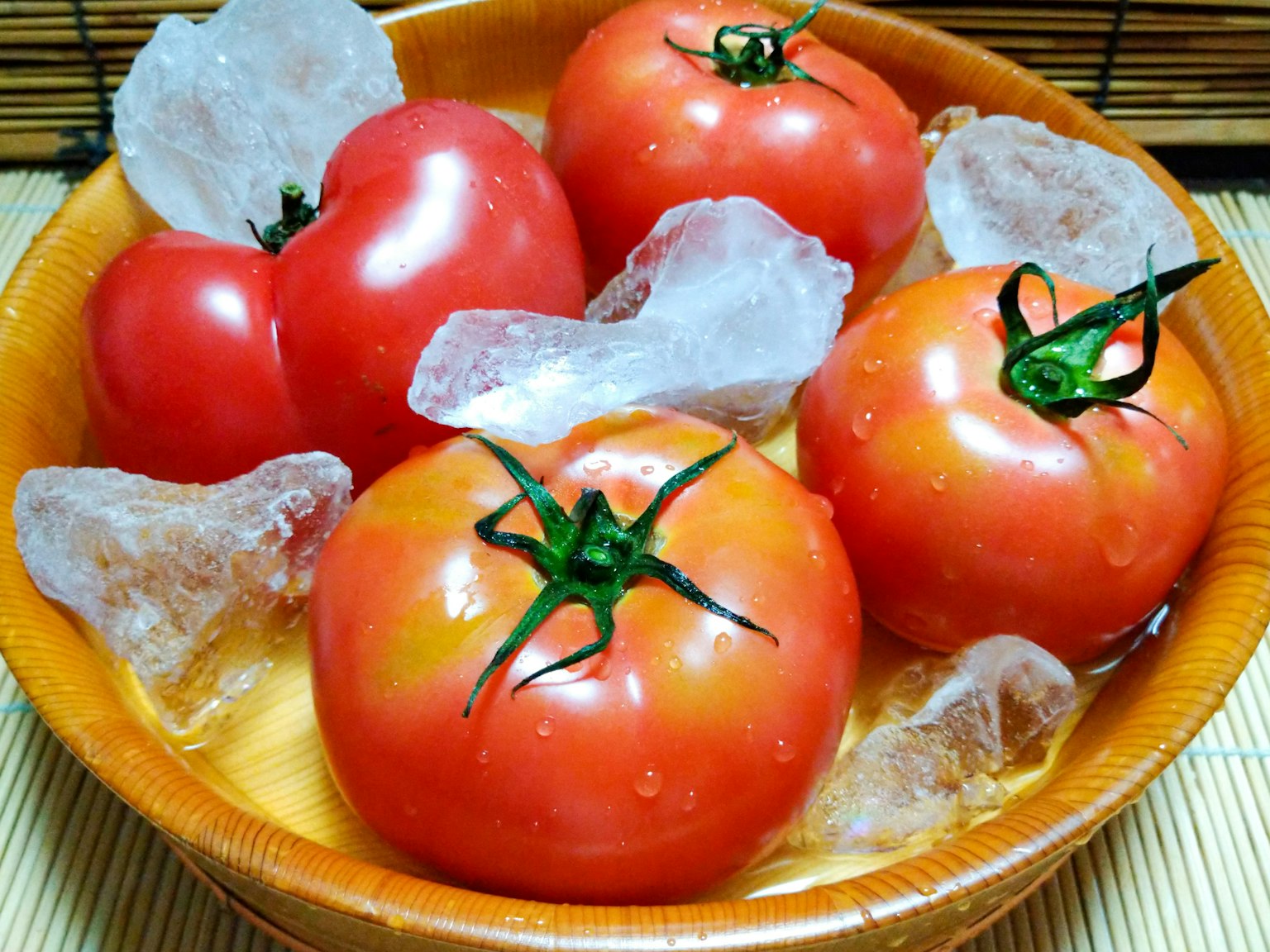 Frische Tomaten in Eis und Wasser in einer Holzschüssel