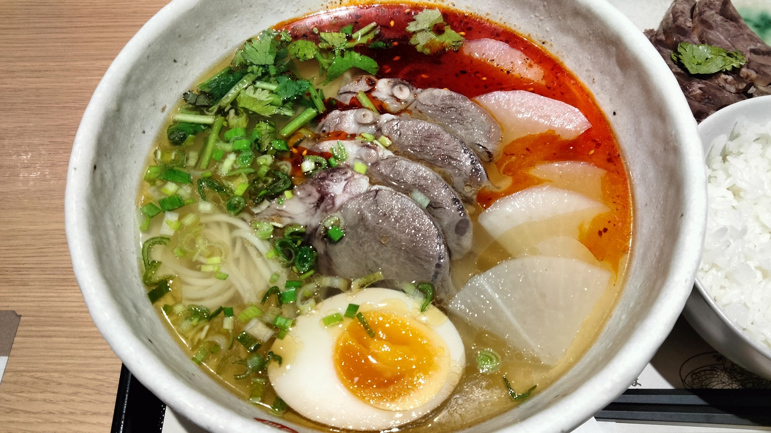 Bol de ramen avec de la viande tranchée, un œuf mollet, des oignons verts et un bouillon riche