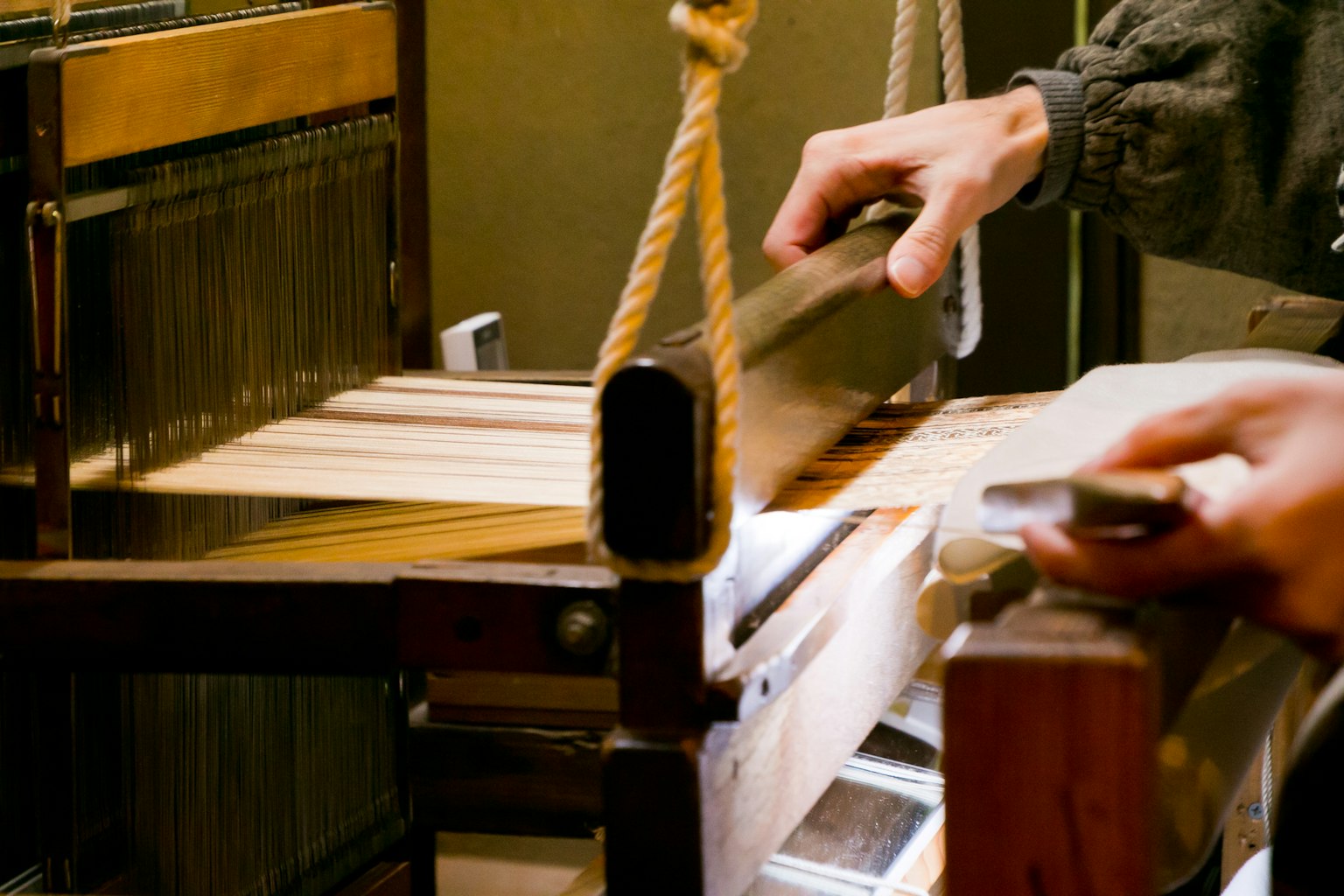 Immagine che cattura mani che tessono tessuto su un telaio