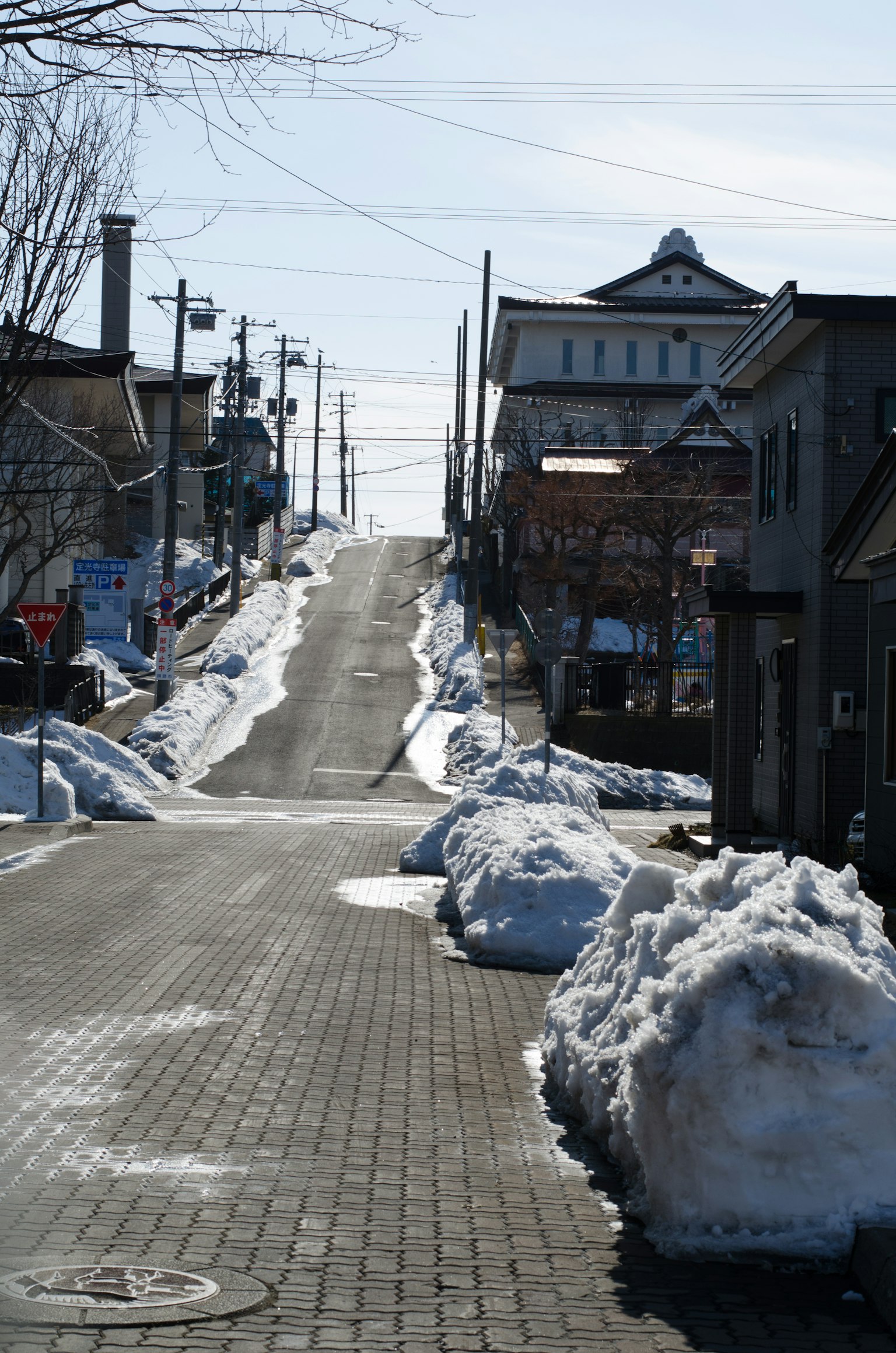 Snow-covered sloped street with quiet townscape