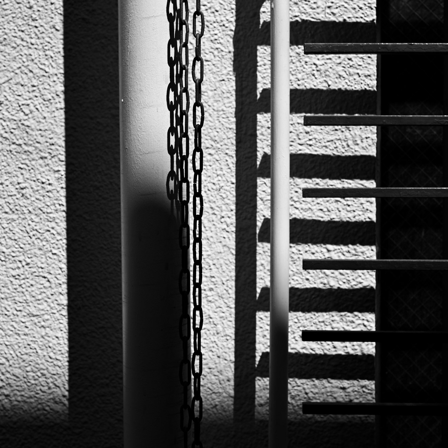 Contrasto di luce e ombra su un muro con una catena e una scala