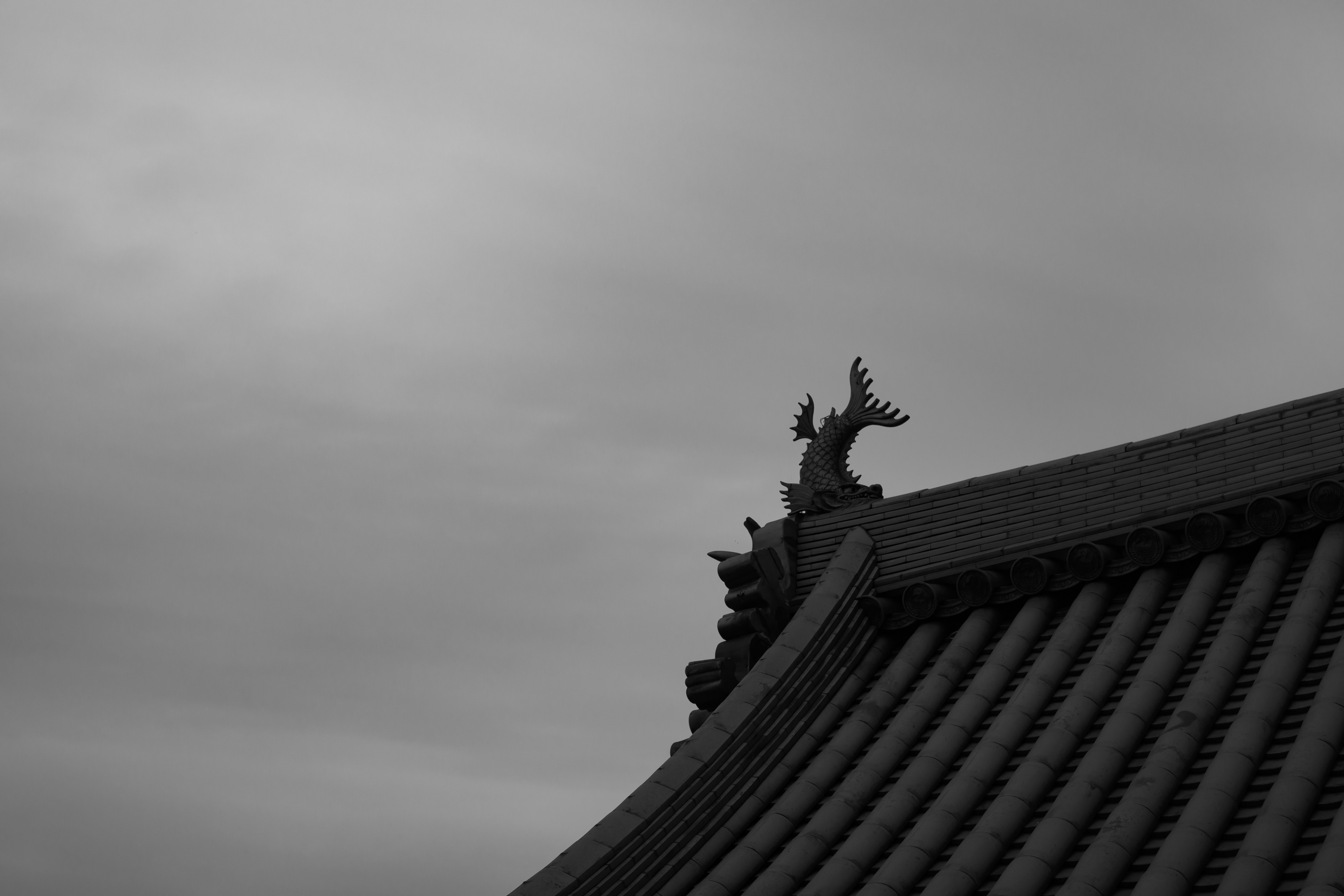 Decorative dragon sculpture on a roof with a cloudy sky