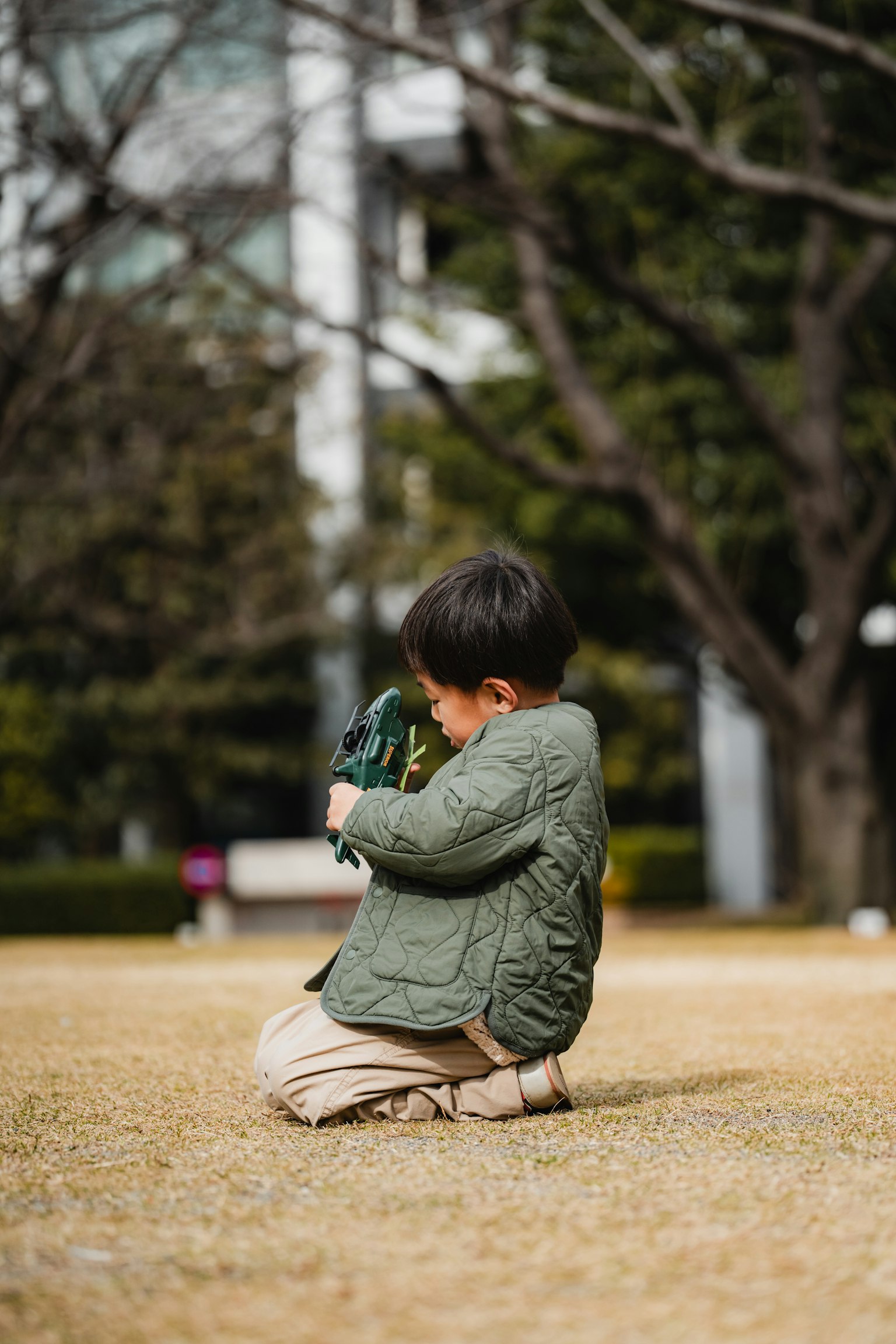 公園で緑の服を着た子供がしゃがんでいる