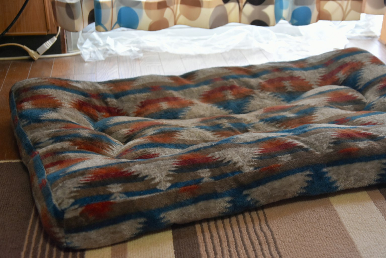 Un coussin à motif coloré sur un sol en bois dans un cadre intérieur confortable