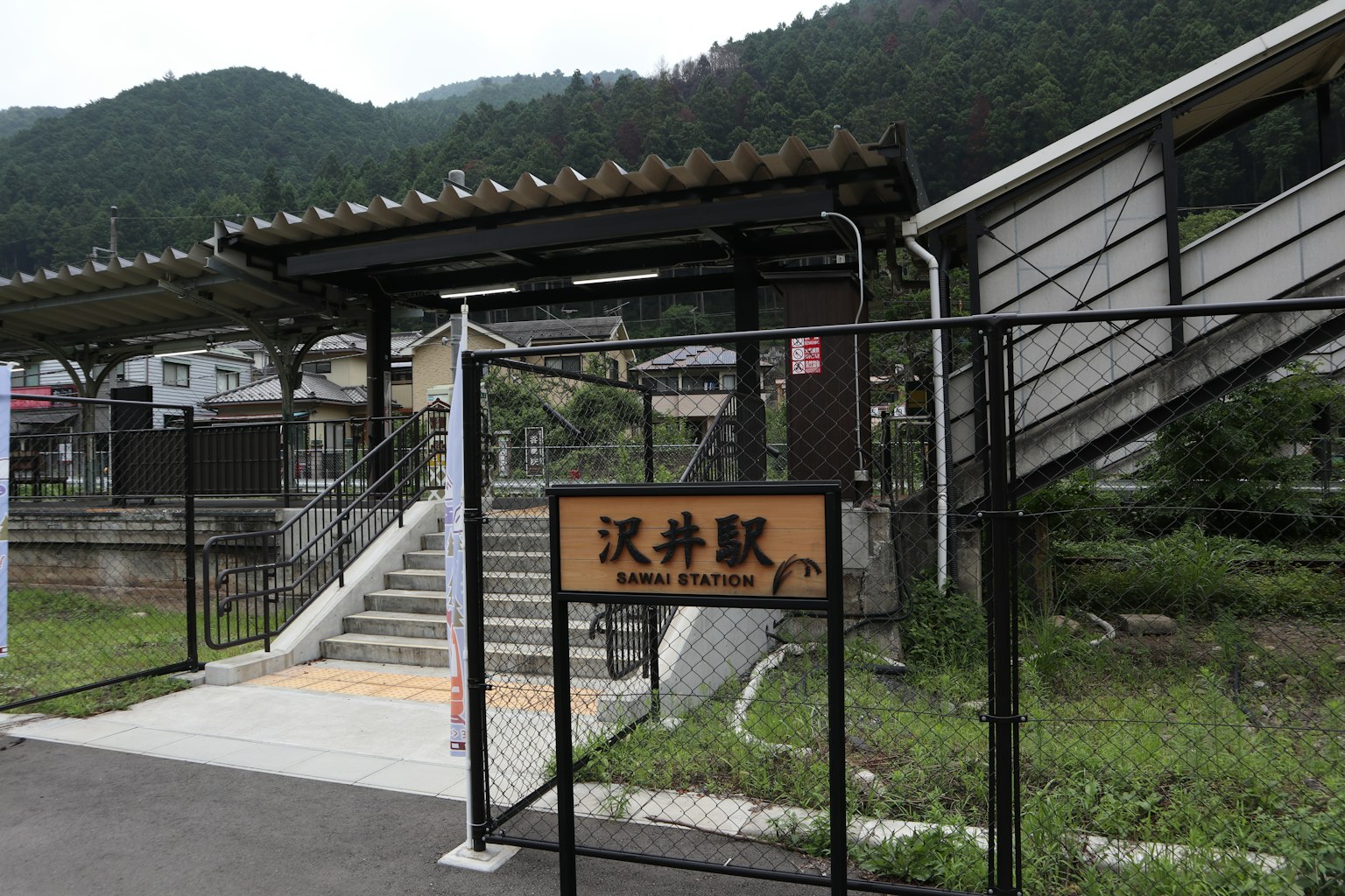 Vue extérieure d'une gare tranquille dans les montagnes avec des escaliers et un panneau