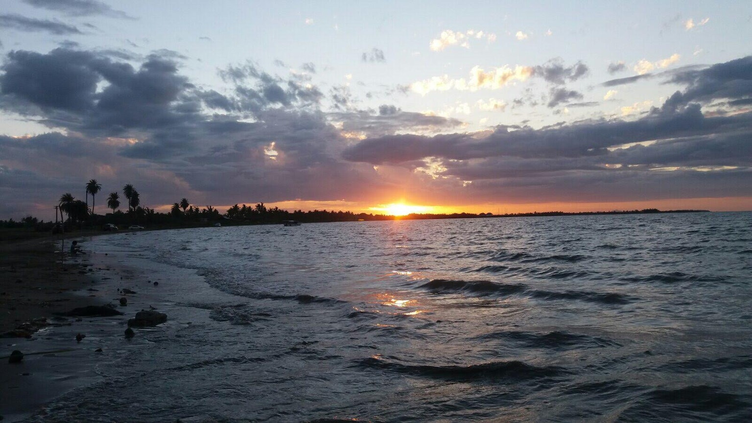 Hermoso atardecer sobre el mar con agua ondulante y nubes dispersas