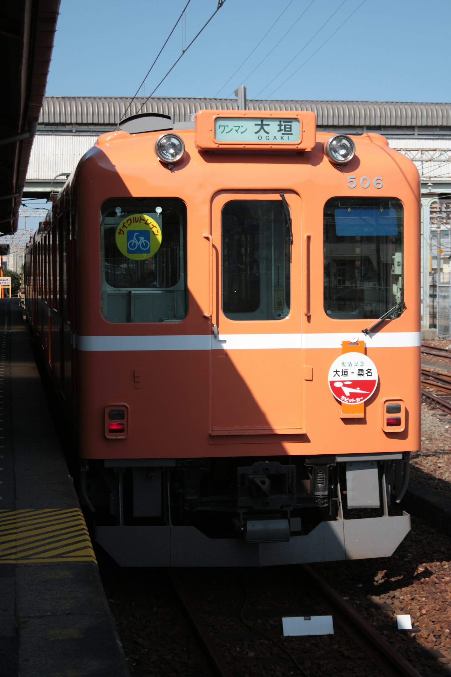 Sebuah kereta oranye terparkir di stasiun